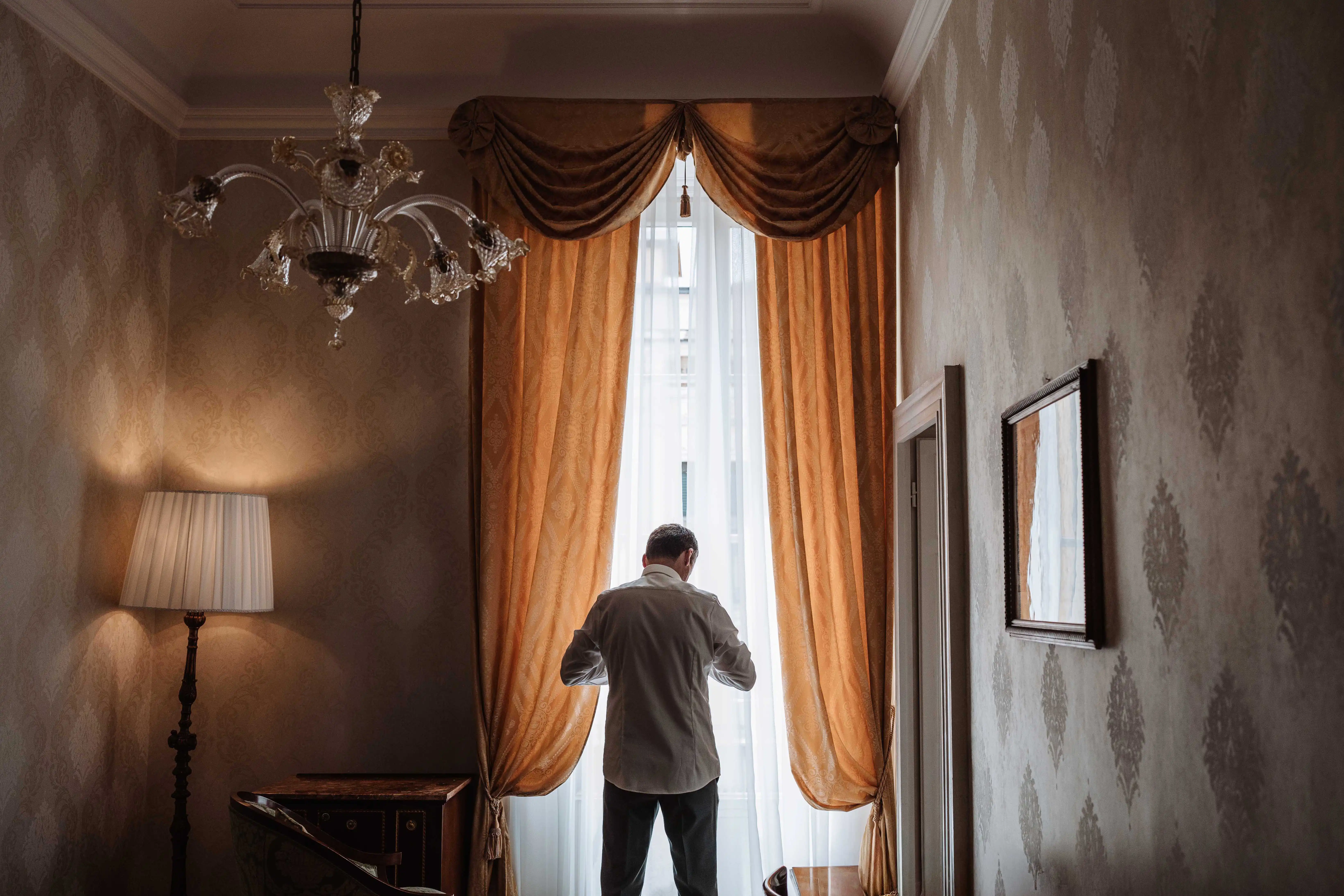groom standing by window natural light getting ready lake como wedding