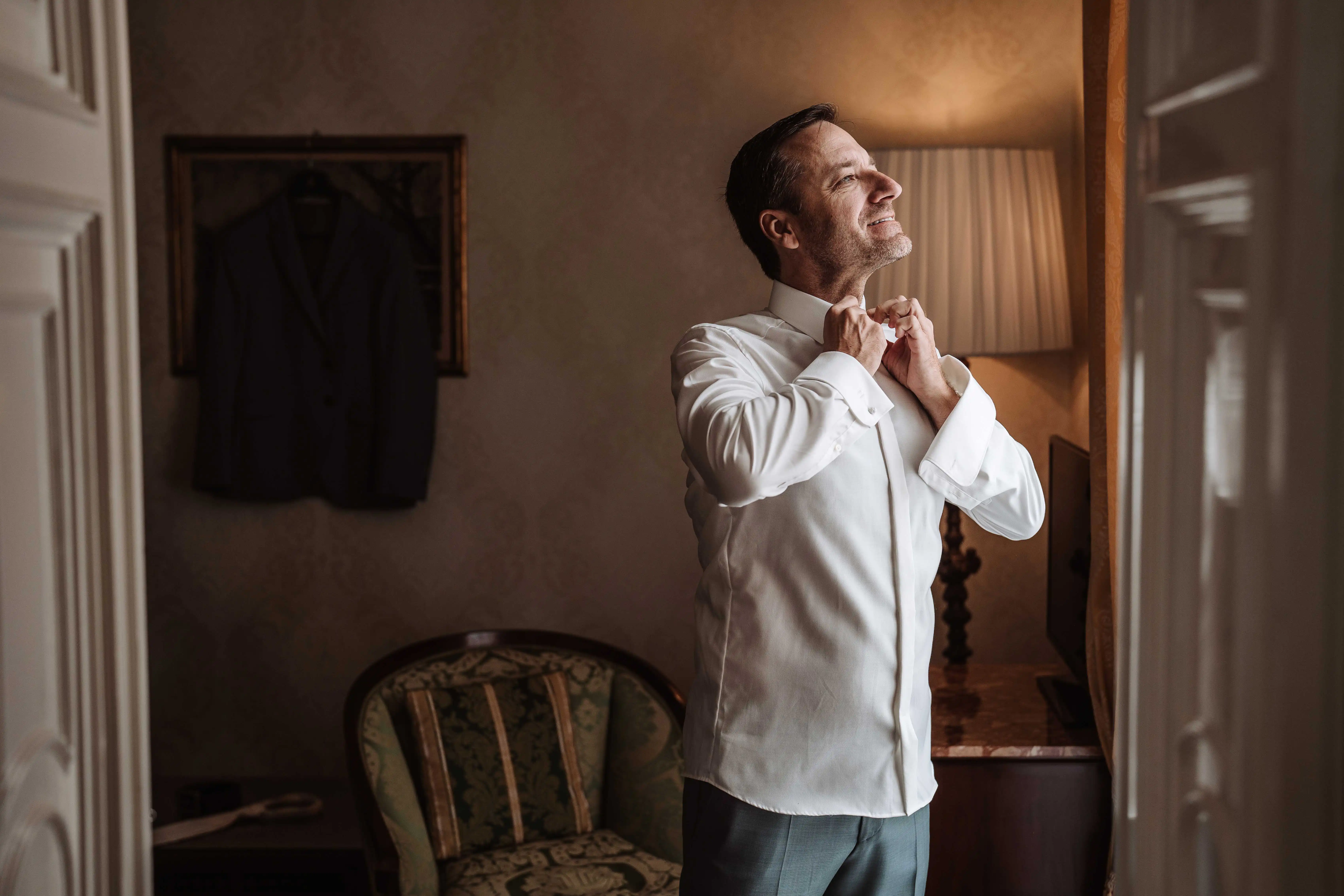 groom adjusting collar elegant preparation moment natural light