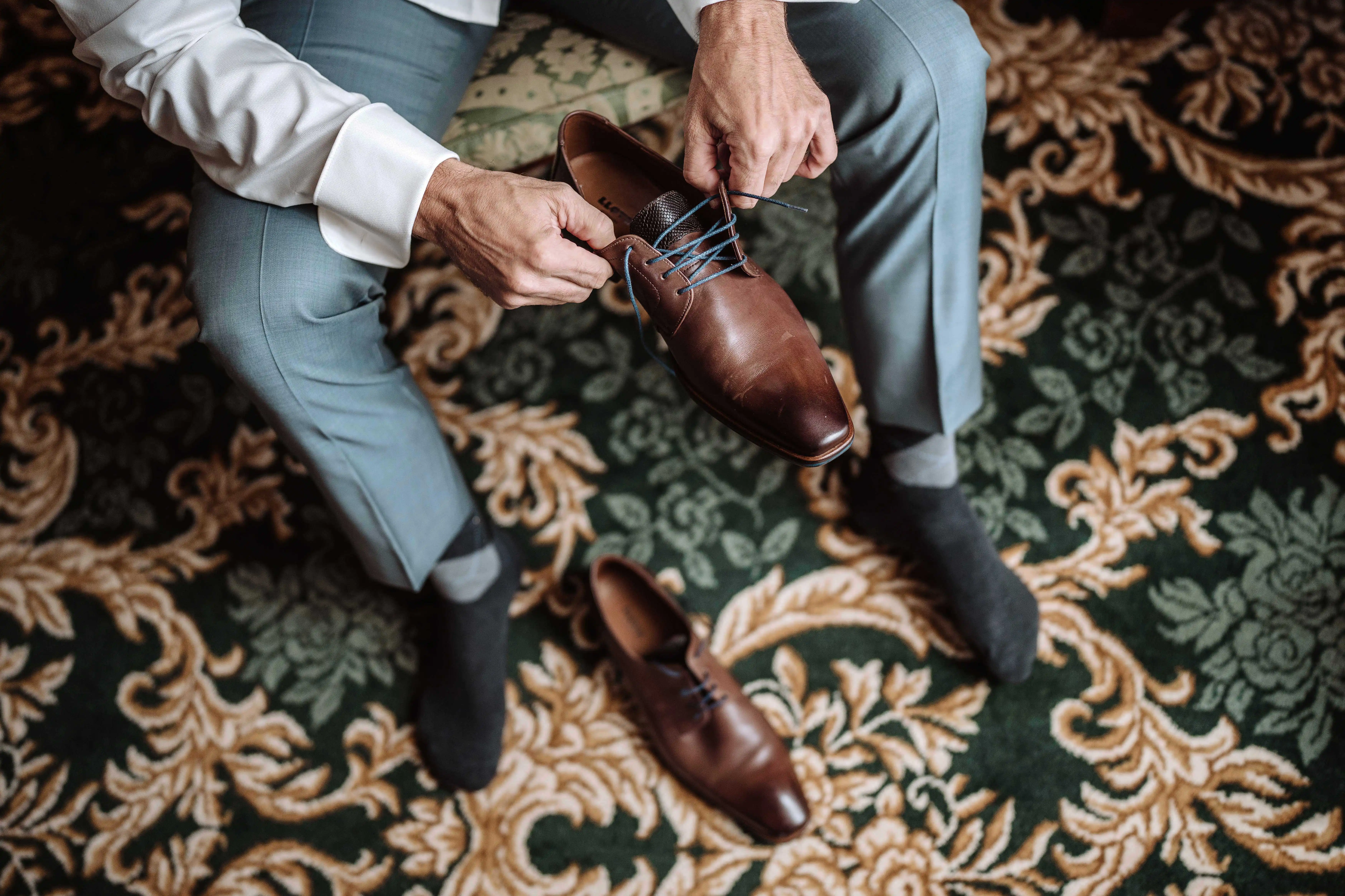 groom putting on brown shoes wedding morning preparation details