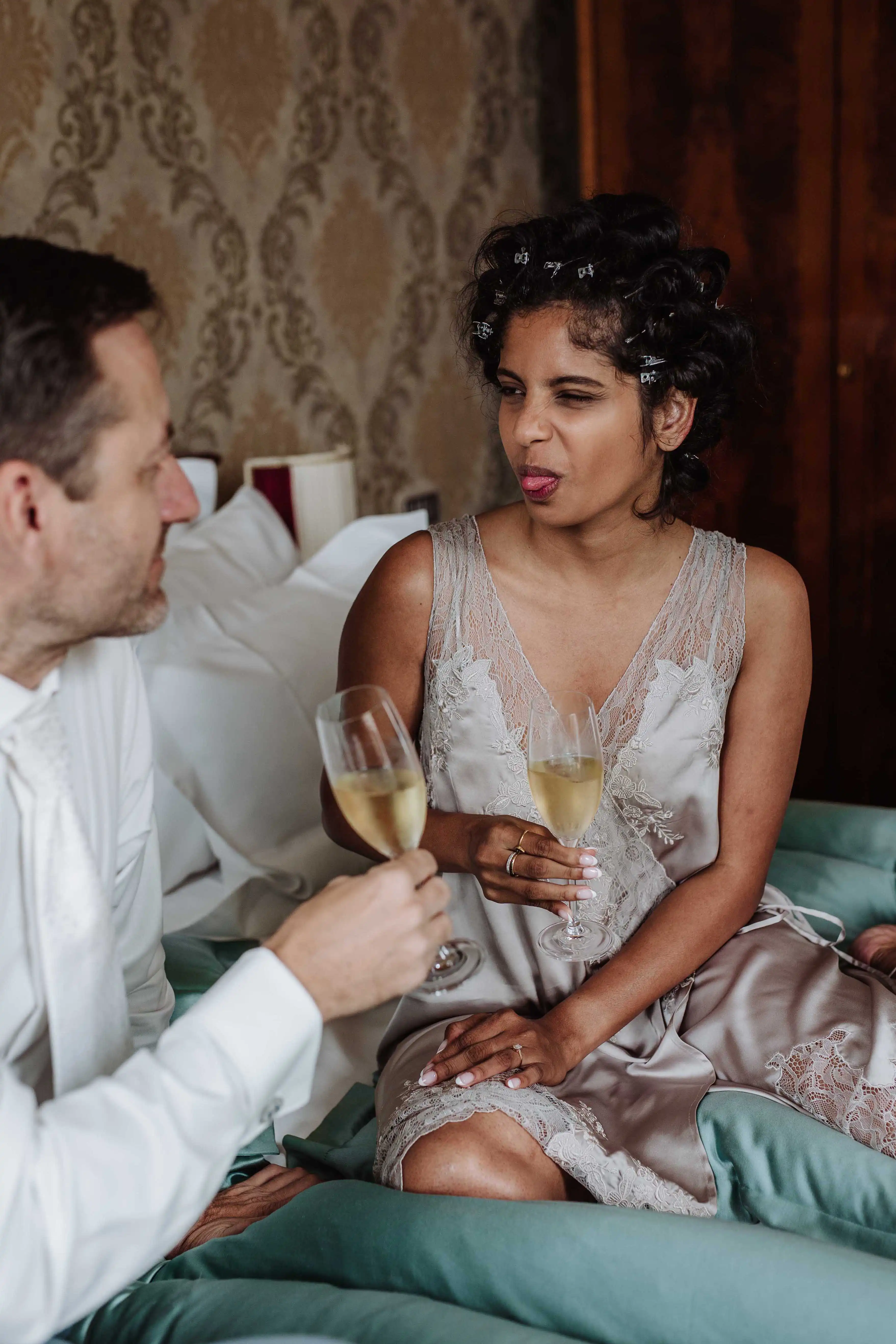 Bride playfully making a face while toasting with groom in a candid moment