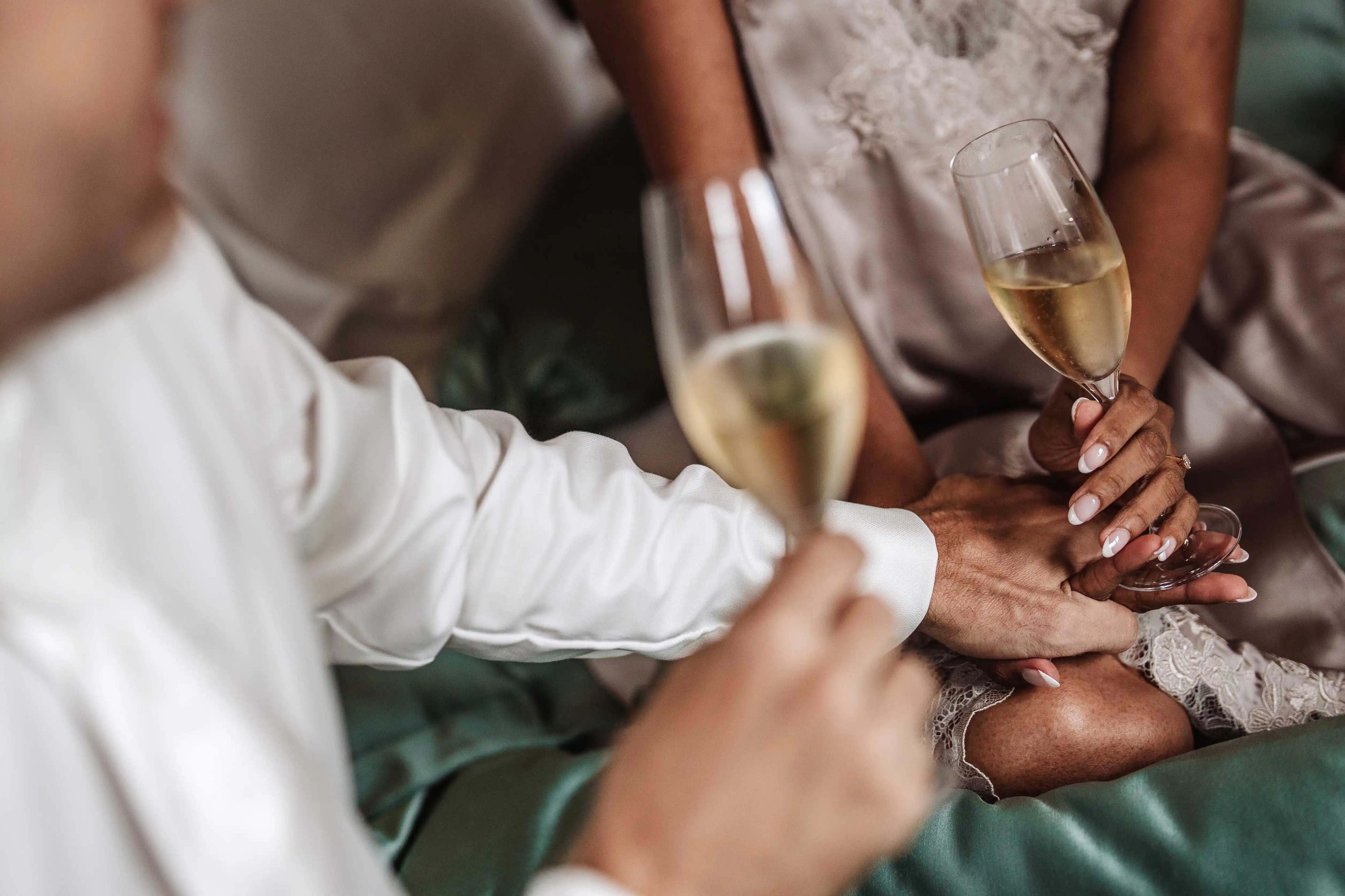 Close-up of bride and groom’s hands holding champagne glasses during an intimate toast