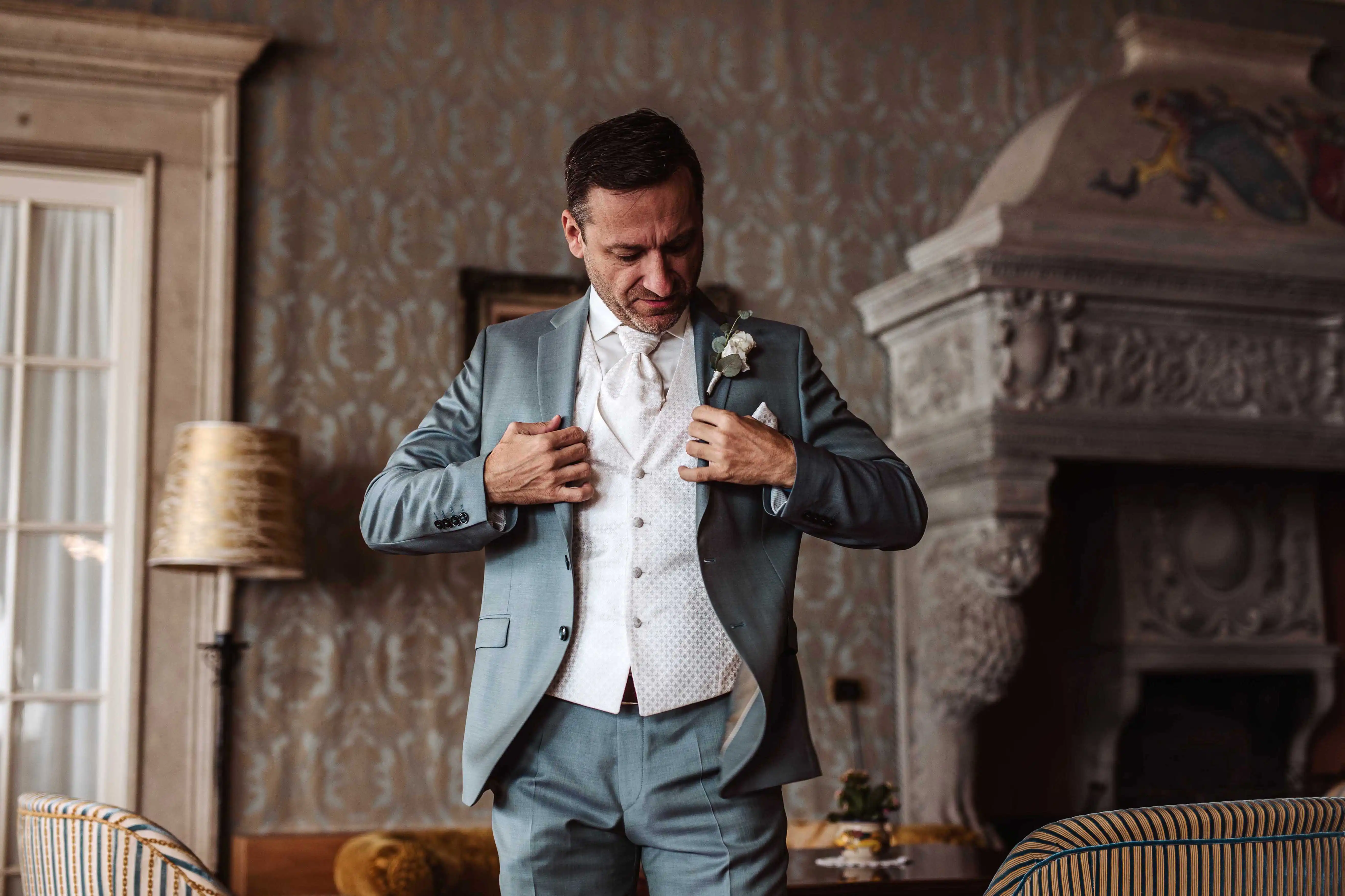 Groom adjusting his jacket in an elegant interior before ceremony