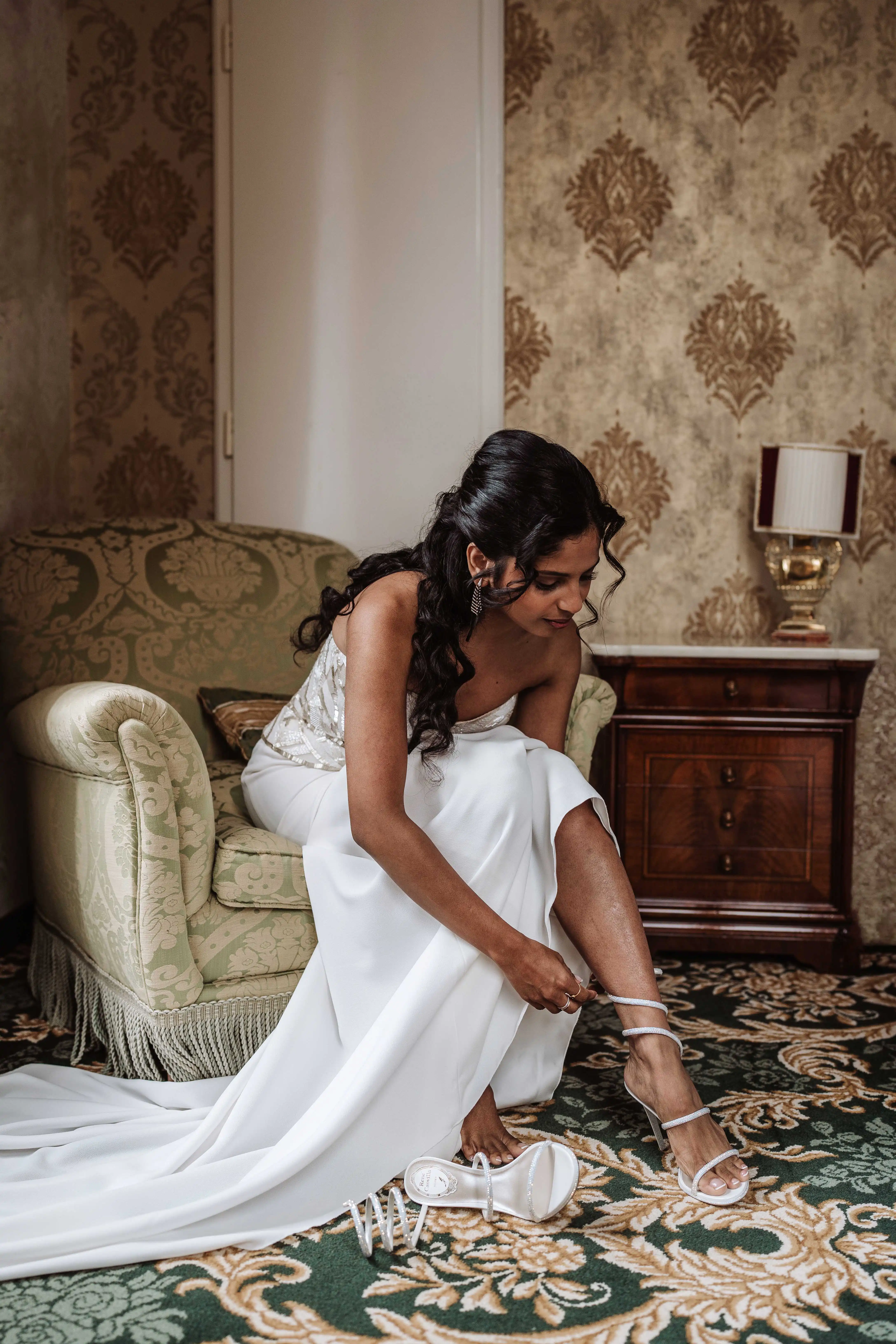 Bride putting on wedding heels in classic Italian villa interior