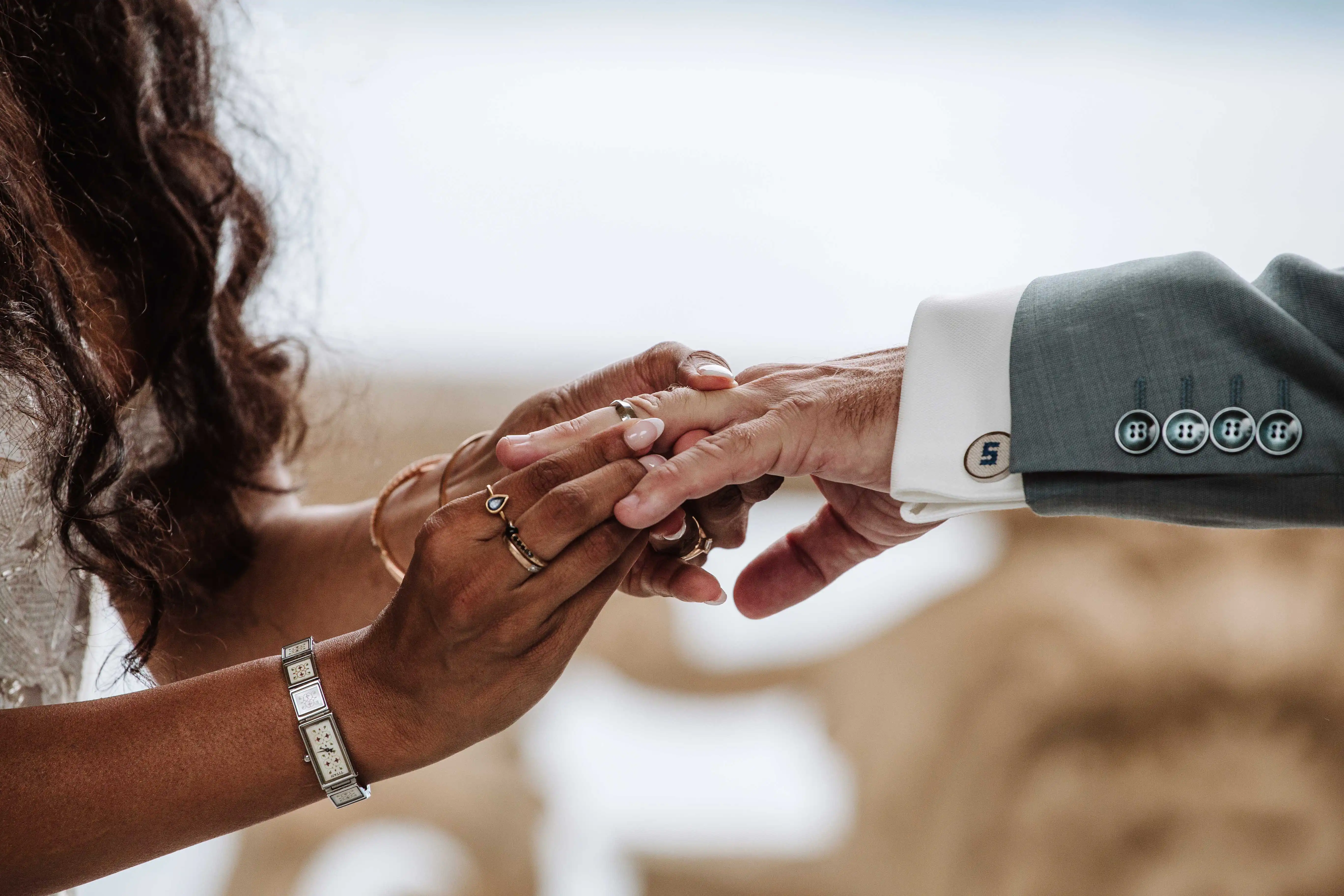 Close-up of wedding rings exchange as groom gently places ring on bride’s finger