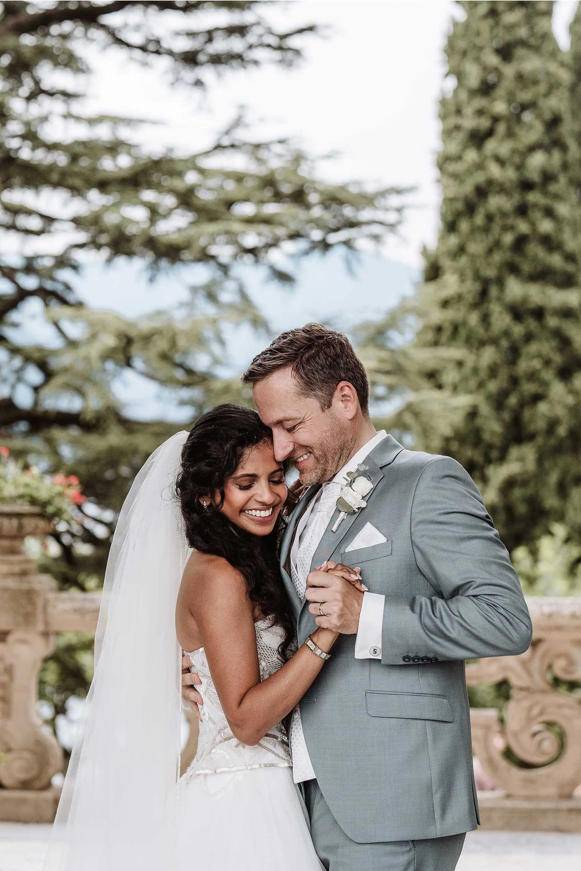 Intimate portrait of bride and groom embracing and smiling in a lush Italian garden setting