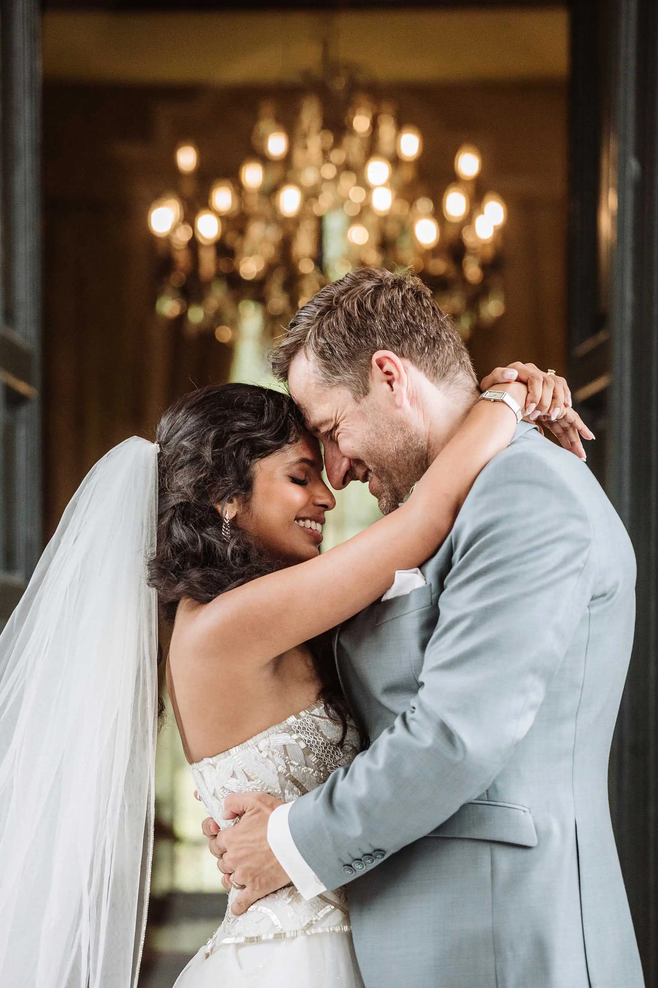 Bride and groom embracing during the wedding ceremony inside a Lake Como villa with chandelier in the background