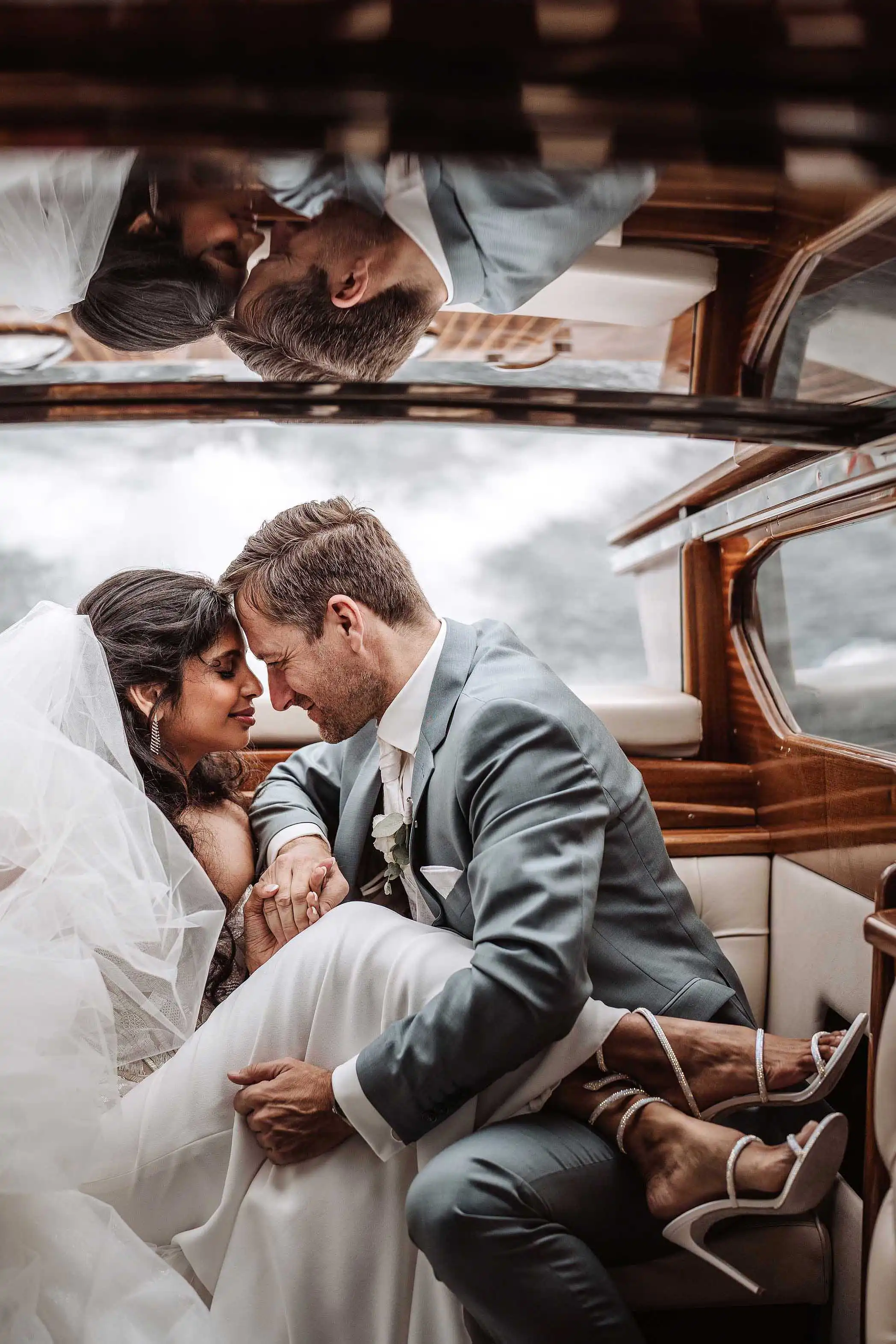 Bride and groom sitting in a classic wooden boat sharing an intimate moment during a Lake Como wedding