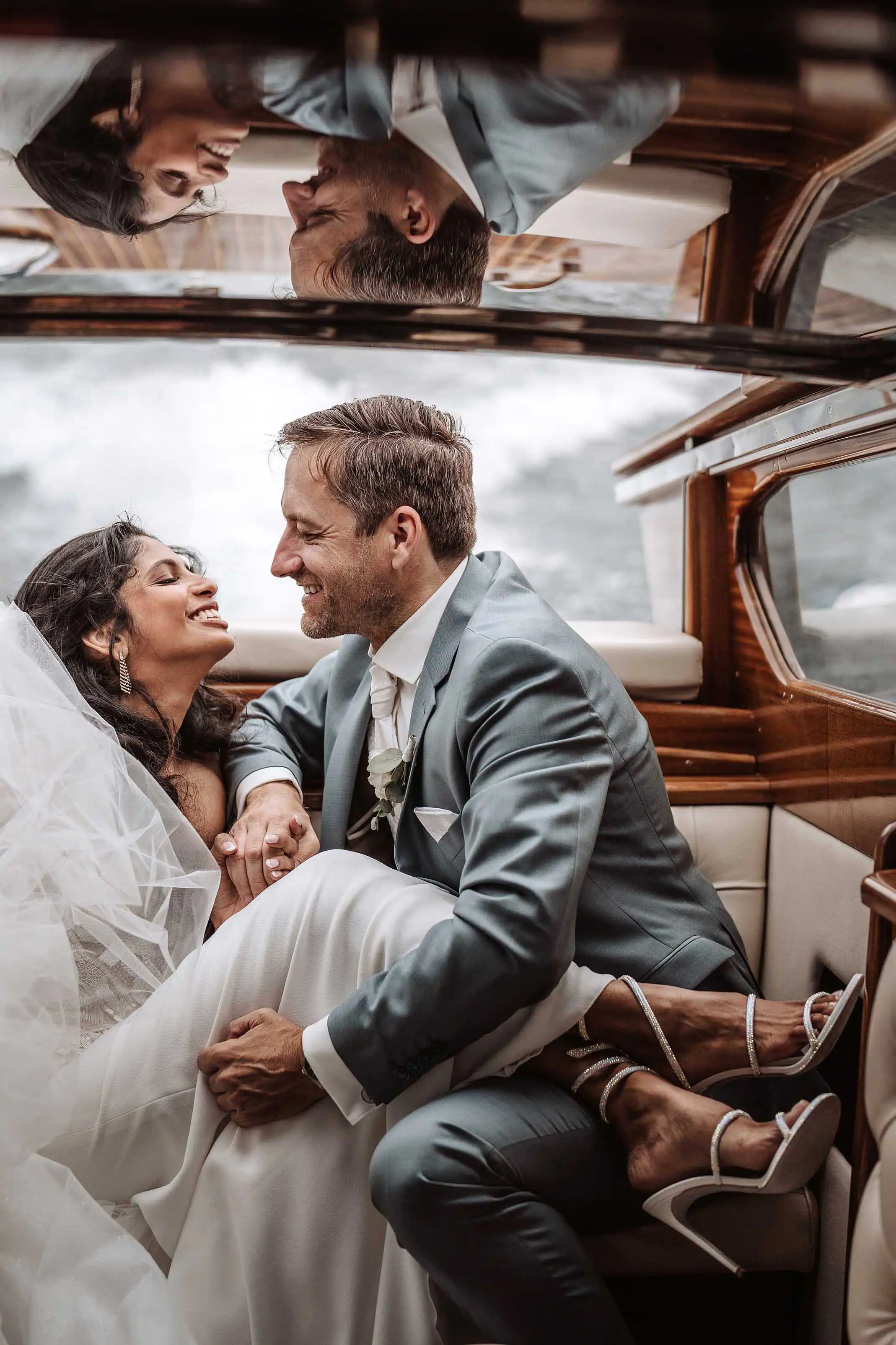Reflection of the couple in the boat as they smile at each other during a romantic Lake Como photo session