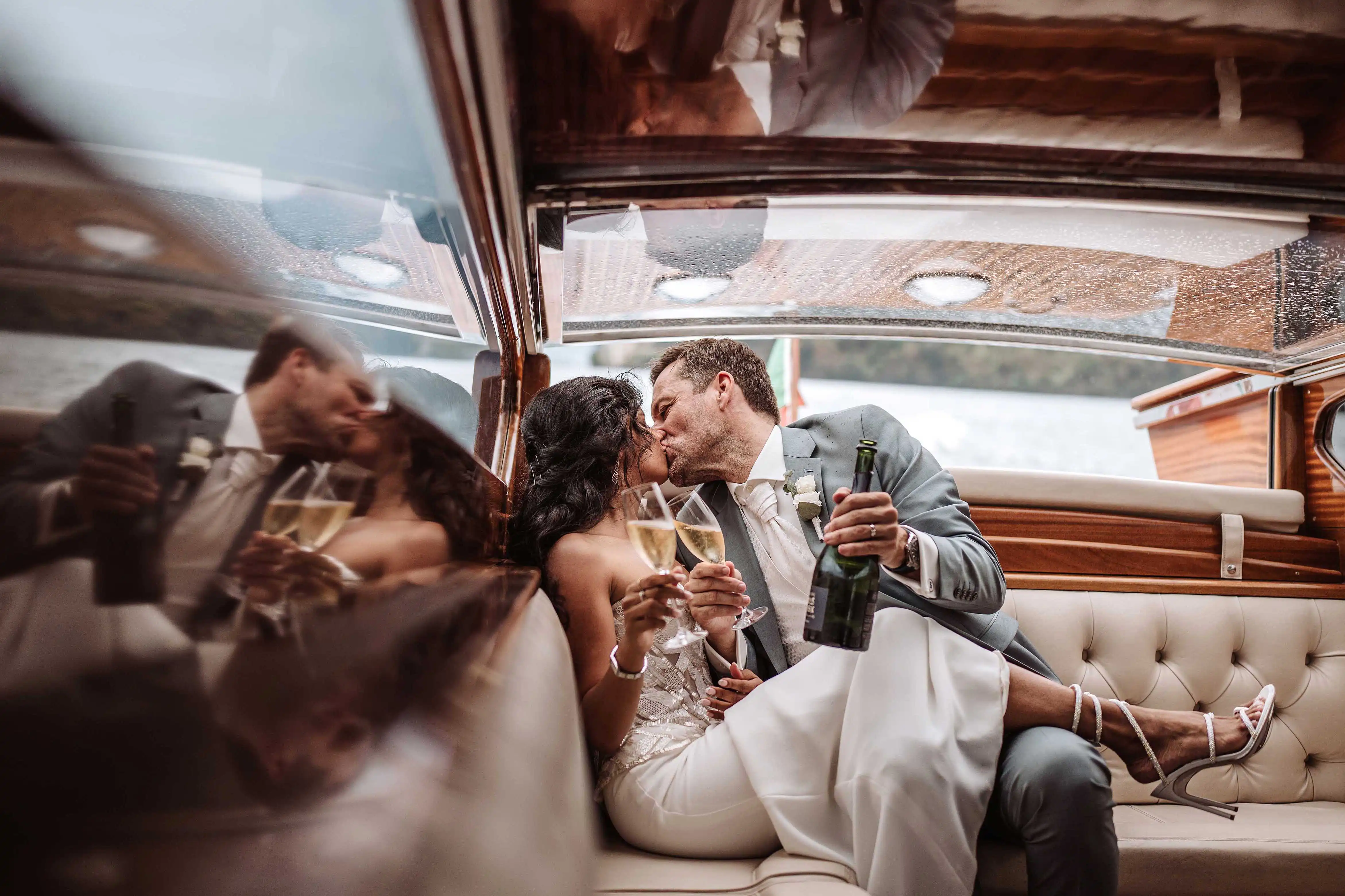 Newlyweds toasting with champagne and kissing in a boat during a Lake Como wedding celebration
