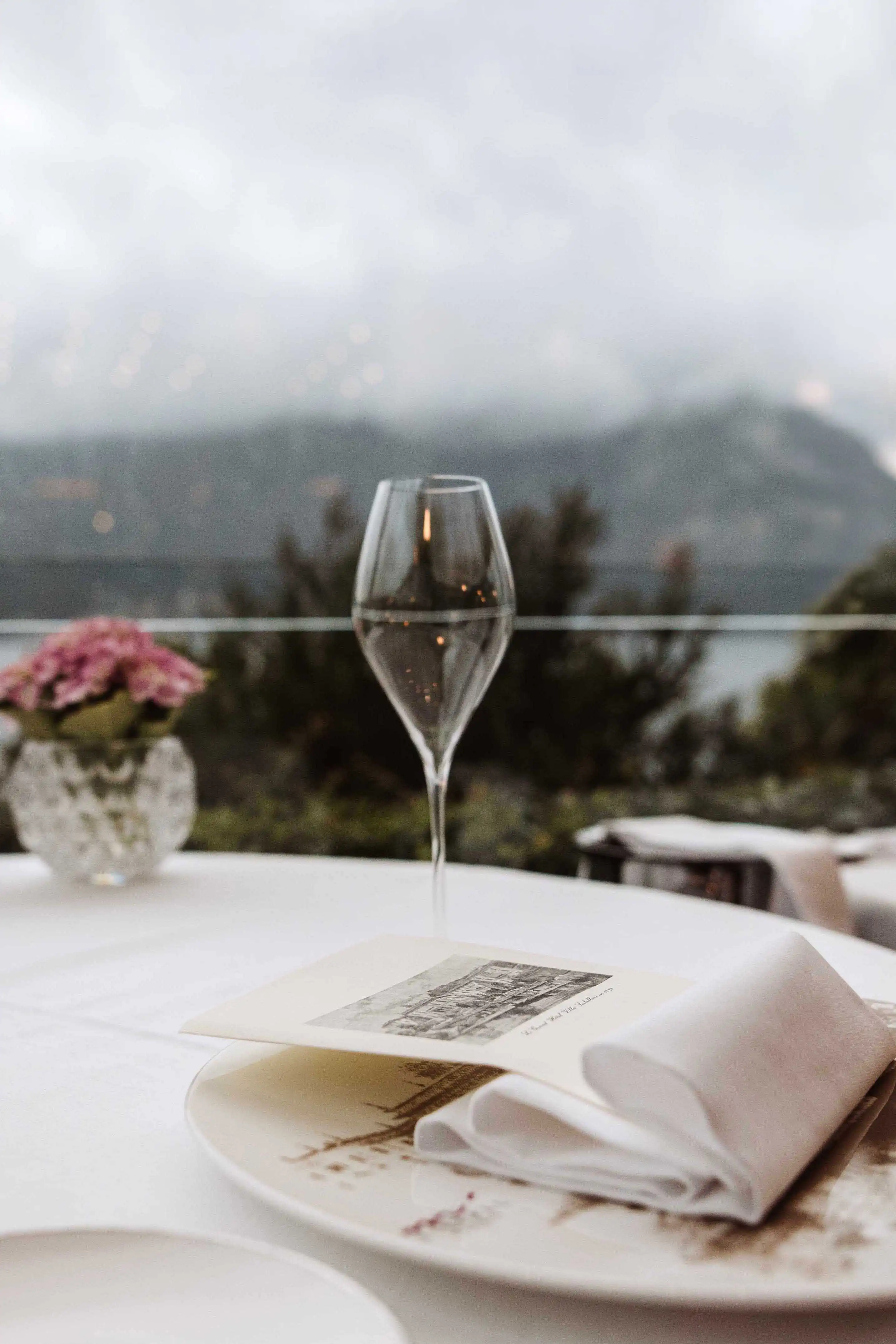 Elegant wedding table detail with wine glass and Lake Como view in the background at a luxury Italian wedding reception
