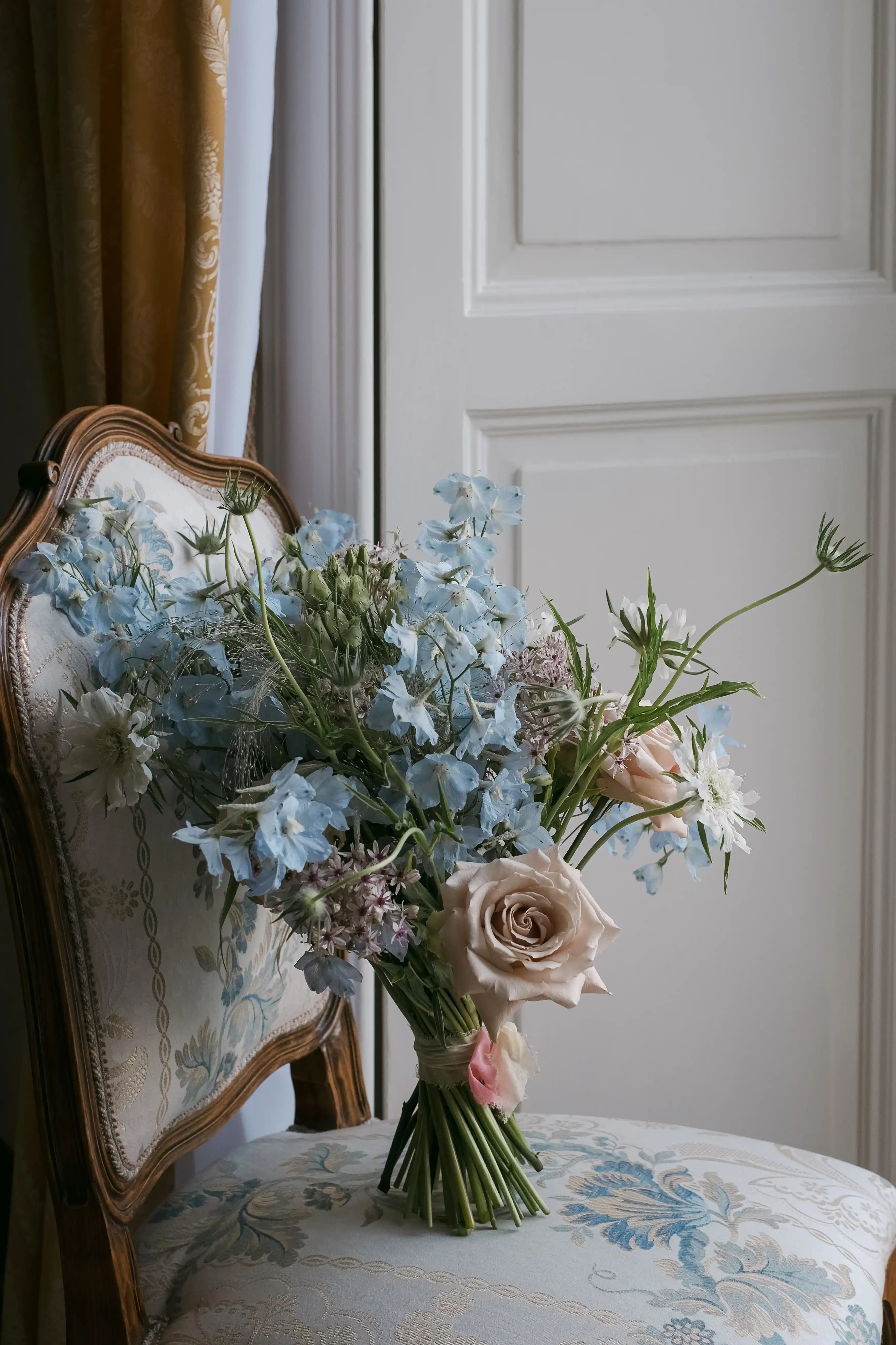 Soft pastel bridal bouquet resting on a vintage chair in an elegant room, refined wedding detail in Lake Como
