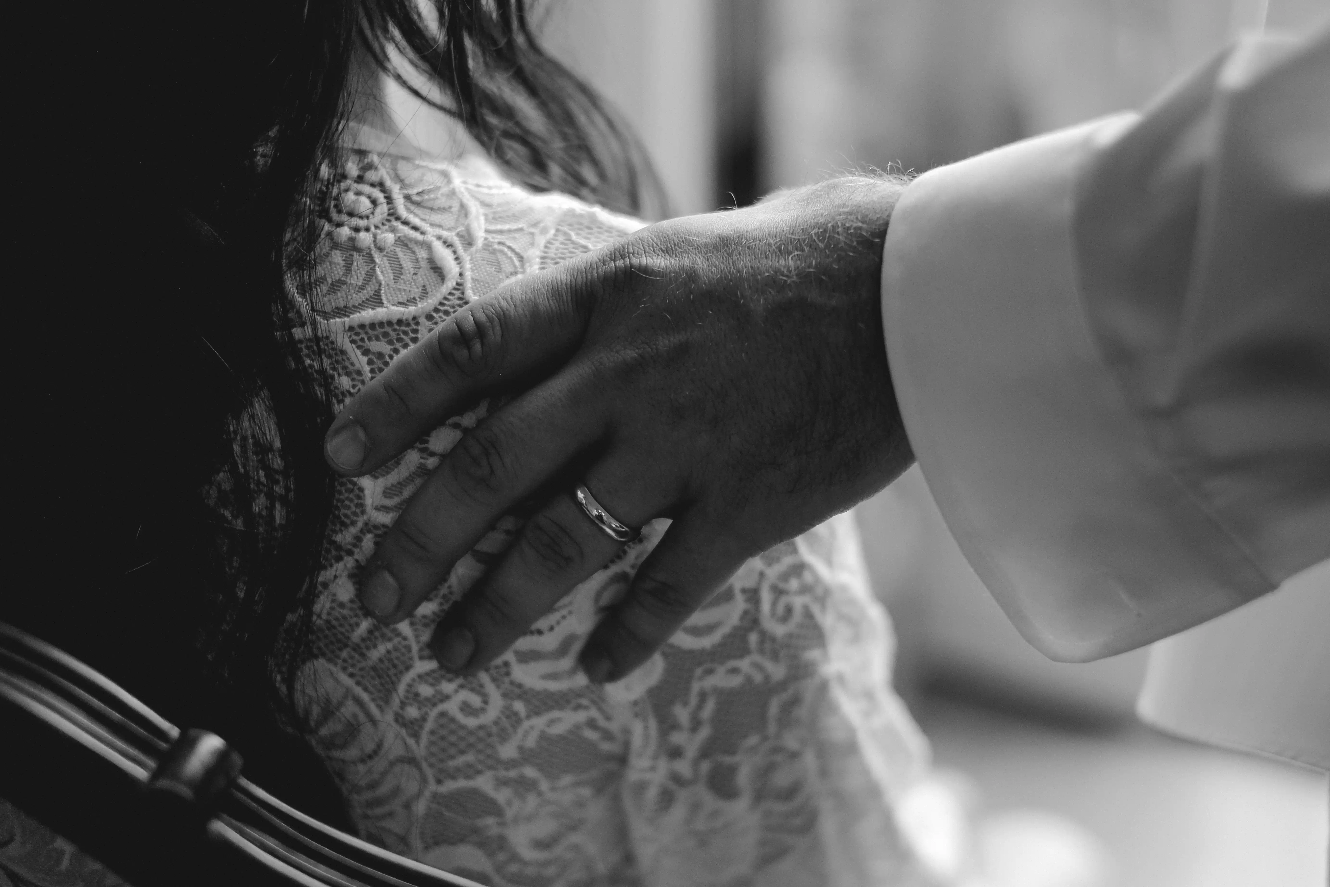 Groom’s hand gently touching the bride in an intimate black and white emotional moment