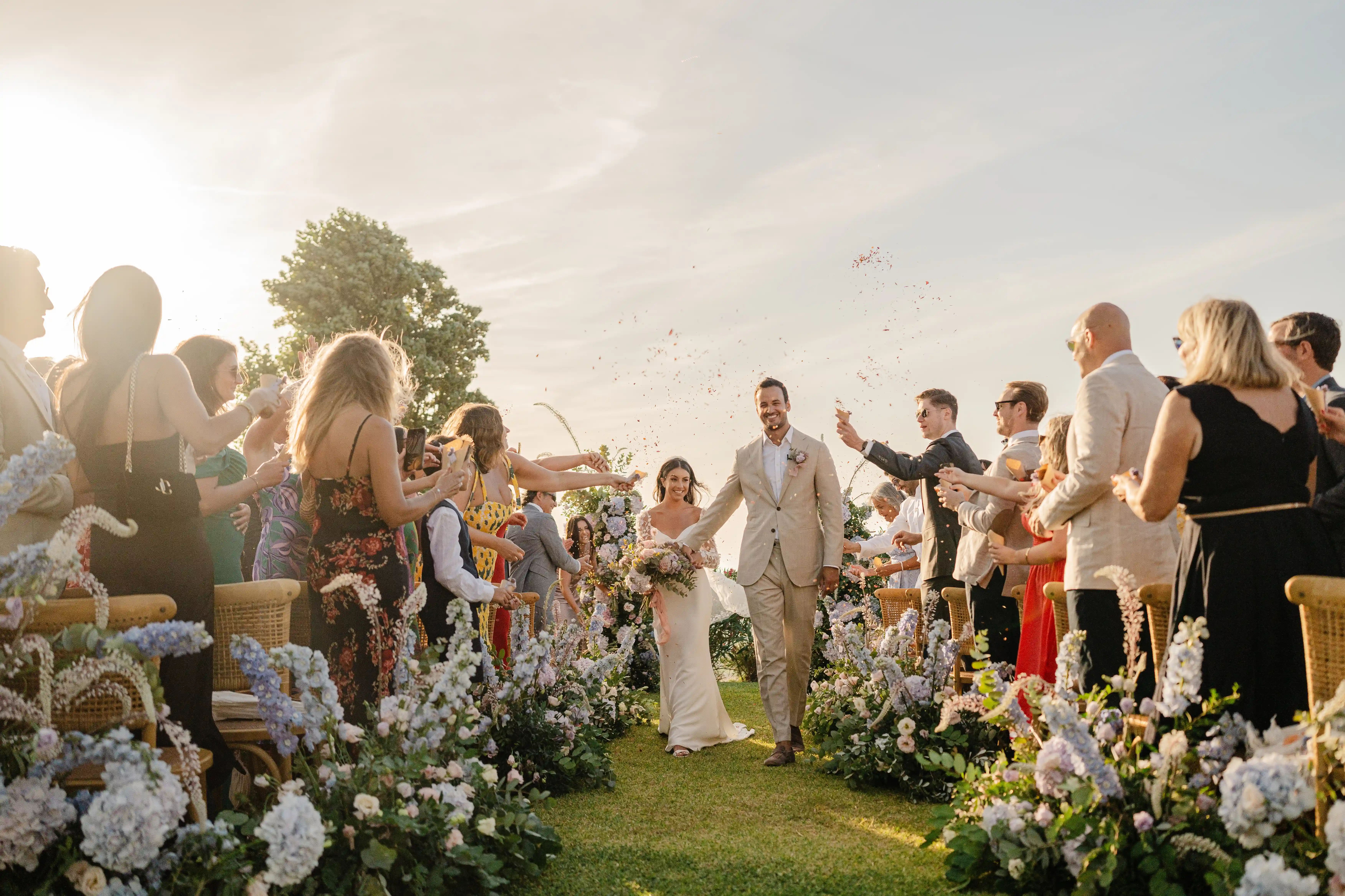 Bride and groom walking down floral aisle during outdoor wedding ceremony in Sicily