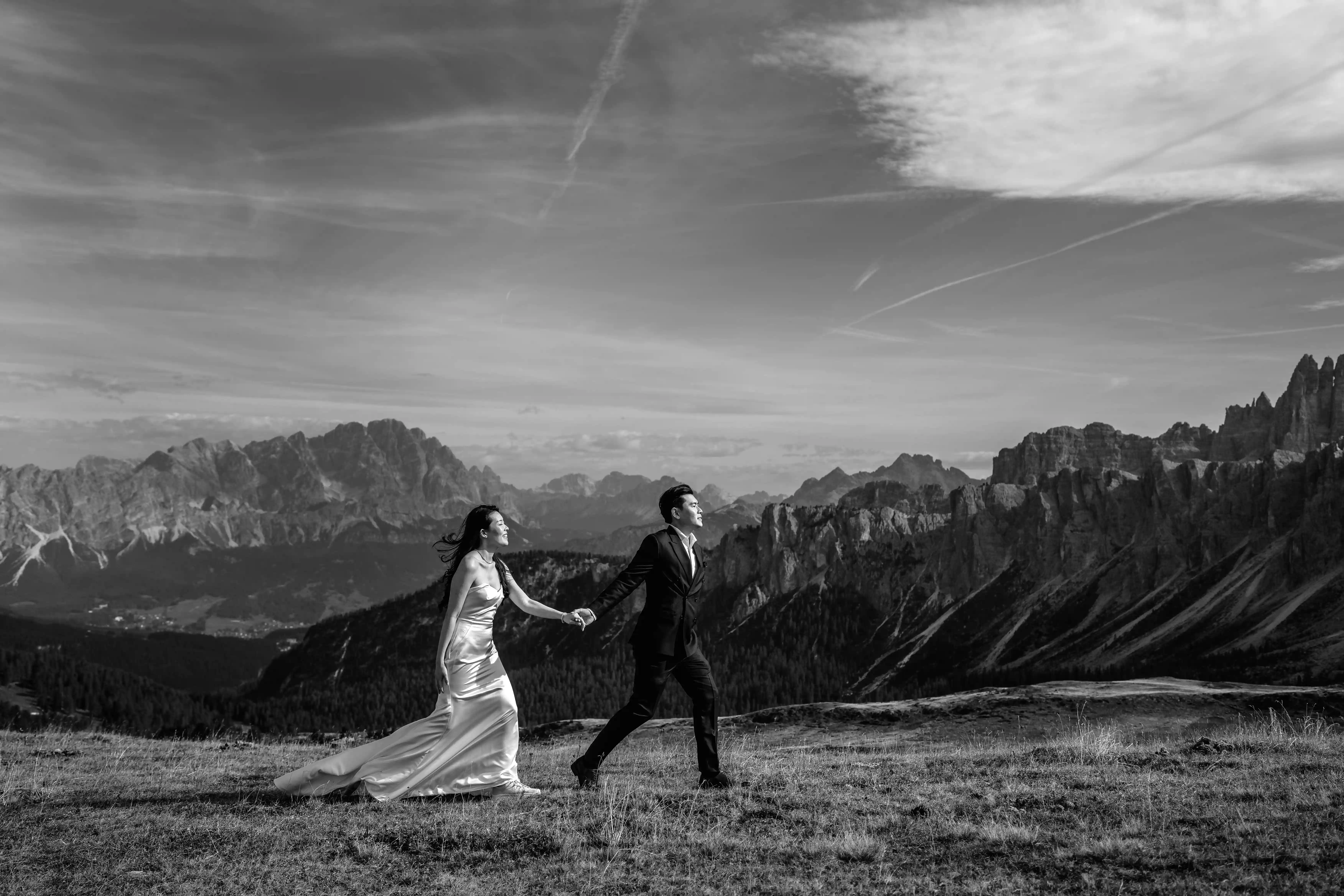 Bride and groom walking across a mountain landscape in the Dolomites during an adventurous elopement