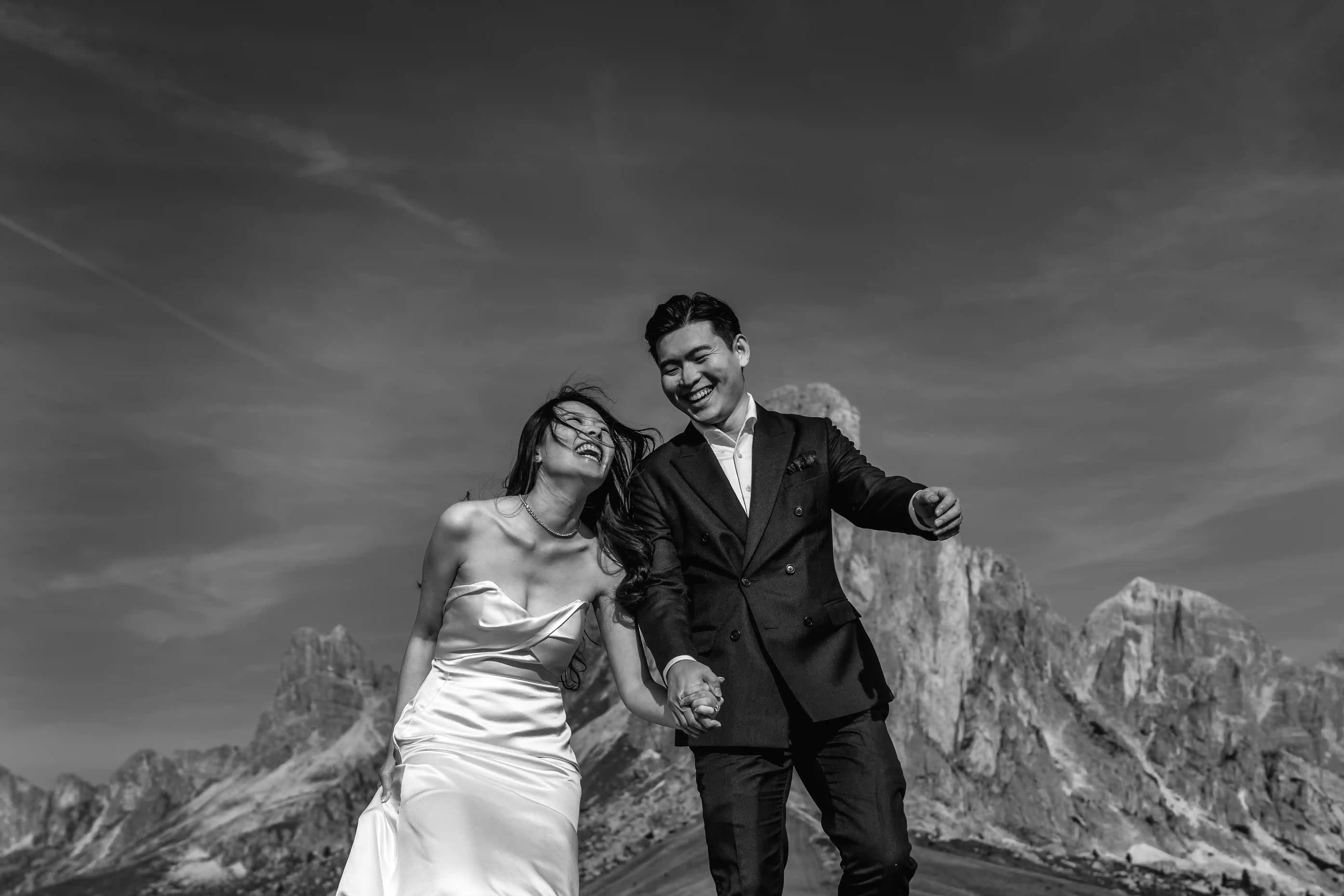 Joyful couple walking and laughing together during a dolomites elopement in black and white