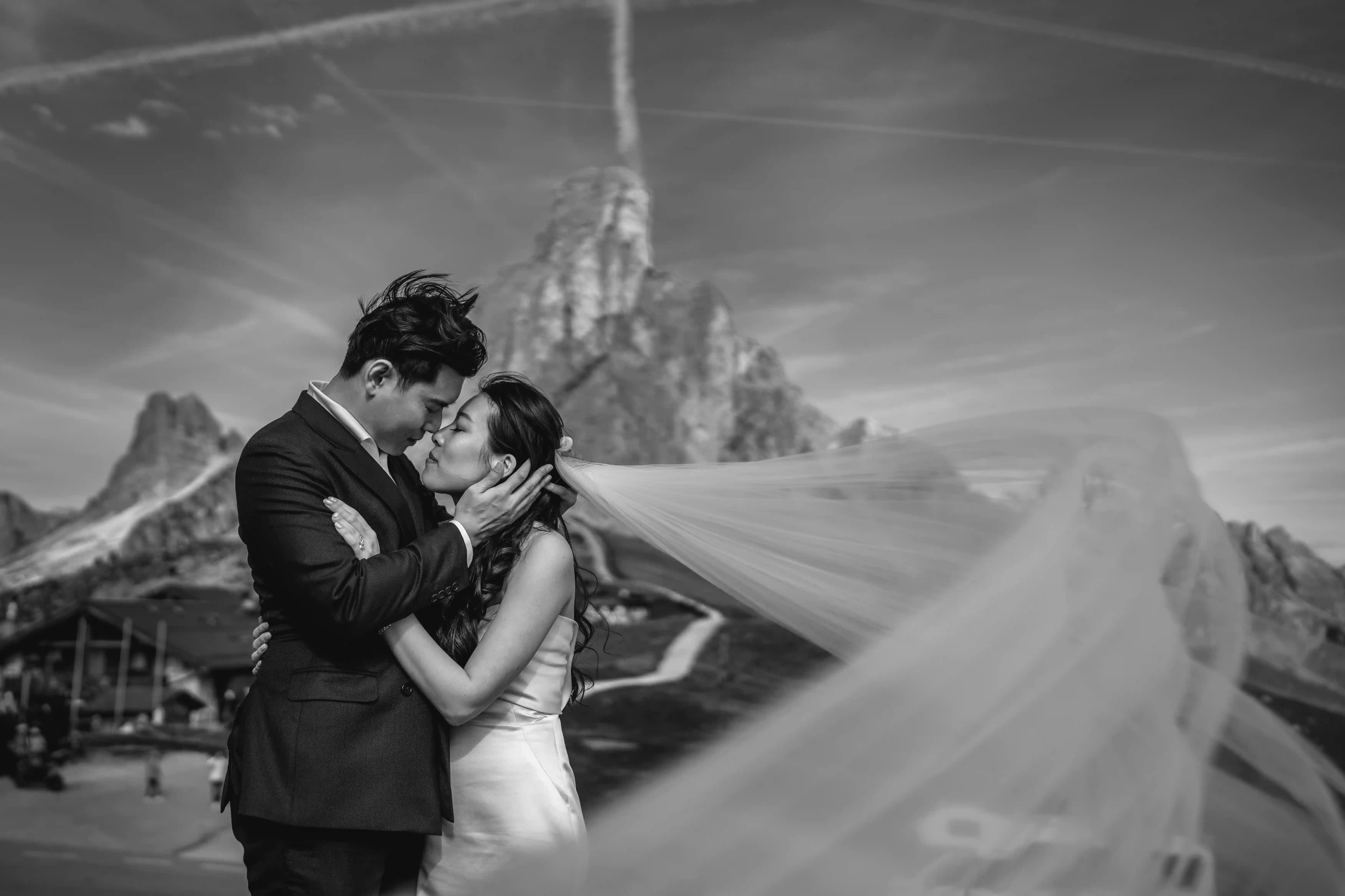Bride and groom embracing with flowing veil during a romantic elopement in the Dolomites mountains