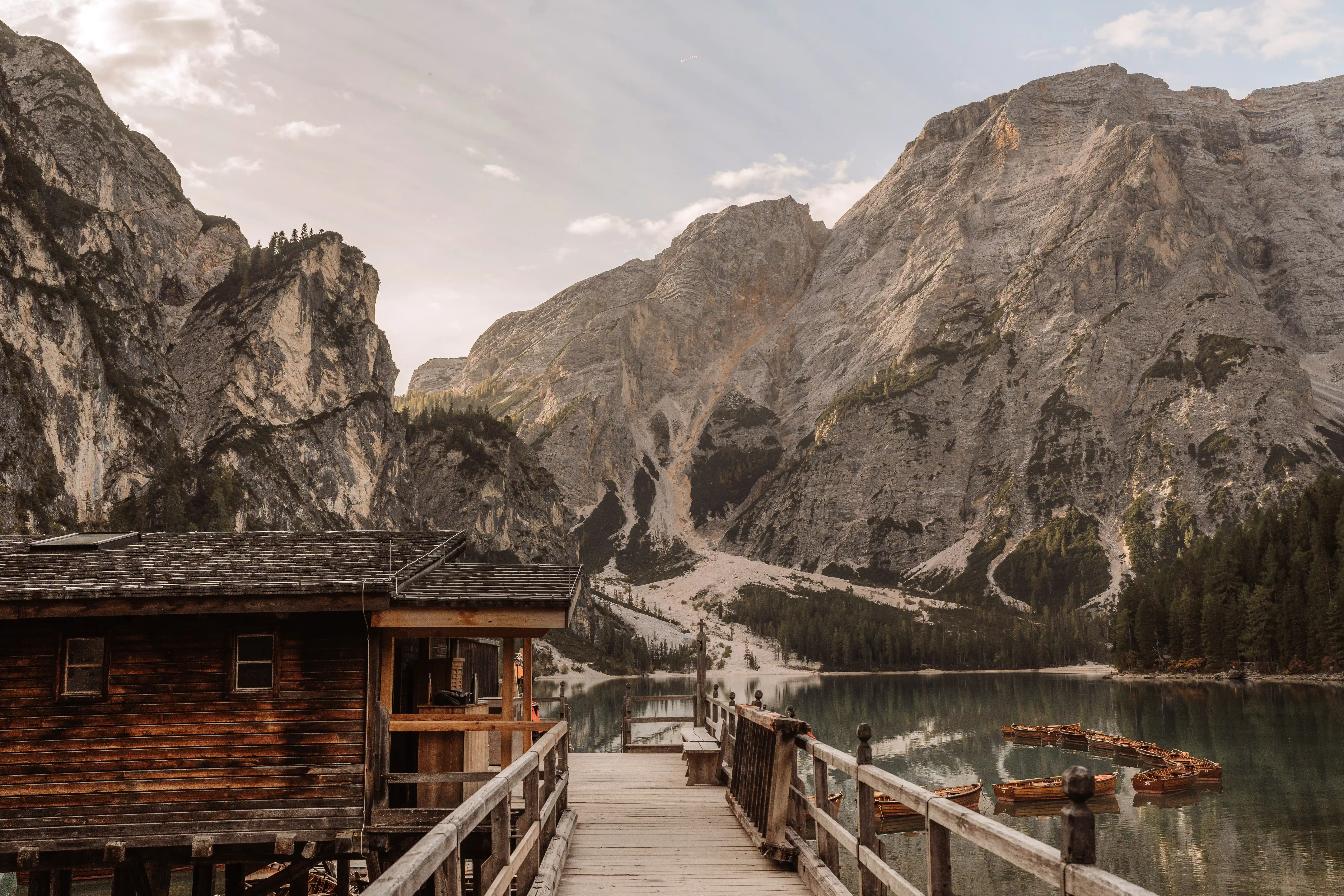Wooden cabin and pier at Lake Braies with boats and Dolomites mountains in the background