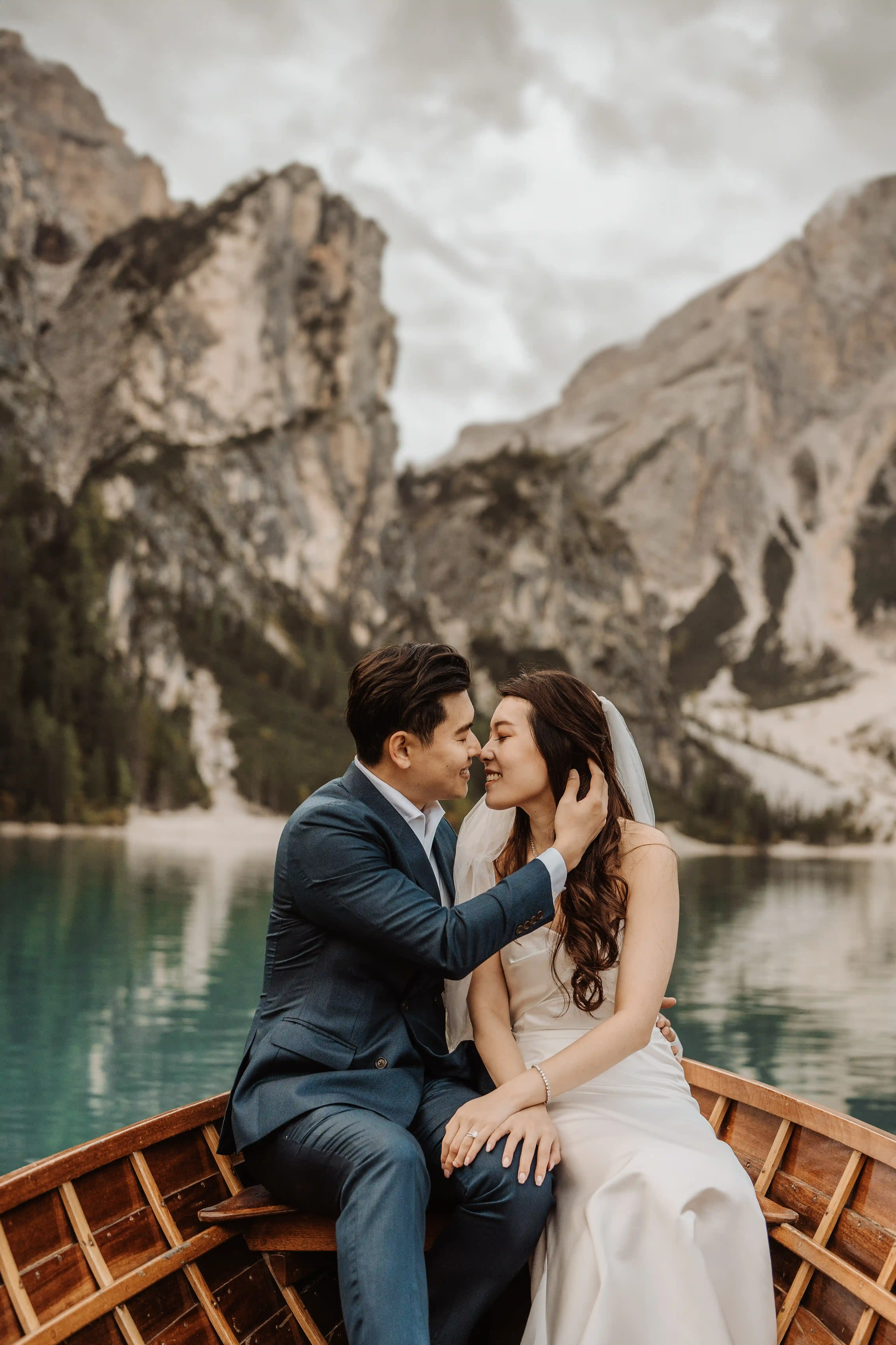 Couple embracing on a wooden boat at Lake Braies during a romantic dolomites elopement