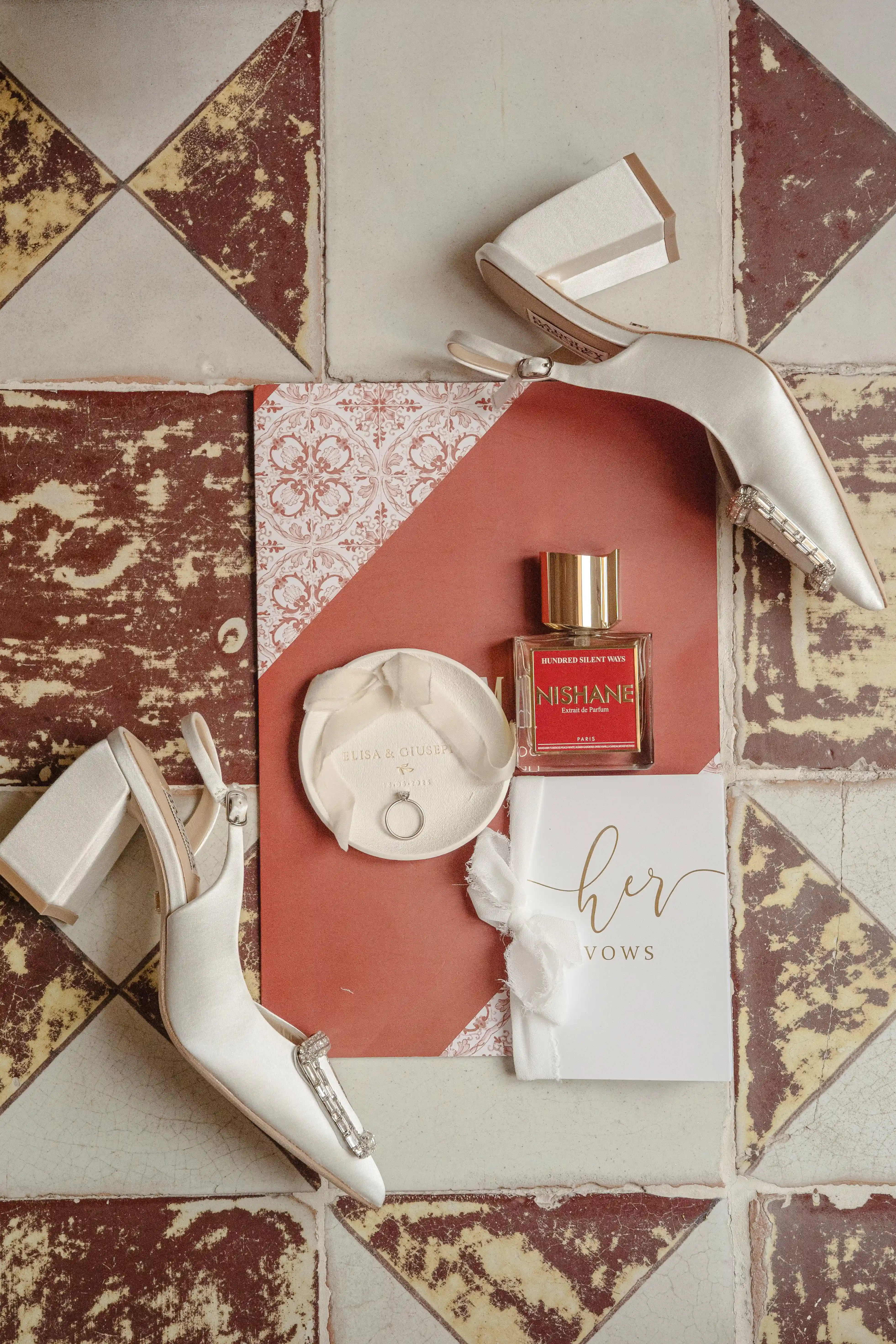 Sicily wedding details with bridal shoes, Nishane perfume, invitations and rings on vintage tiled floor