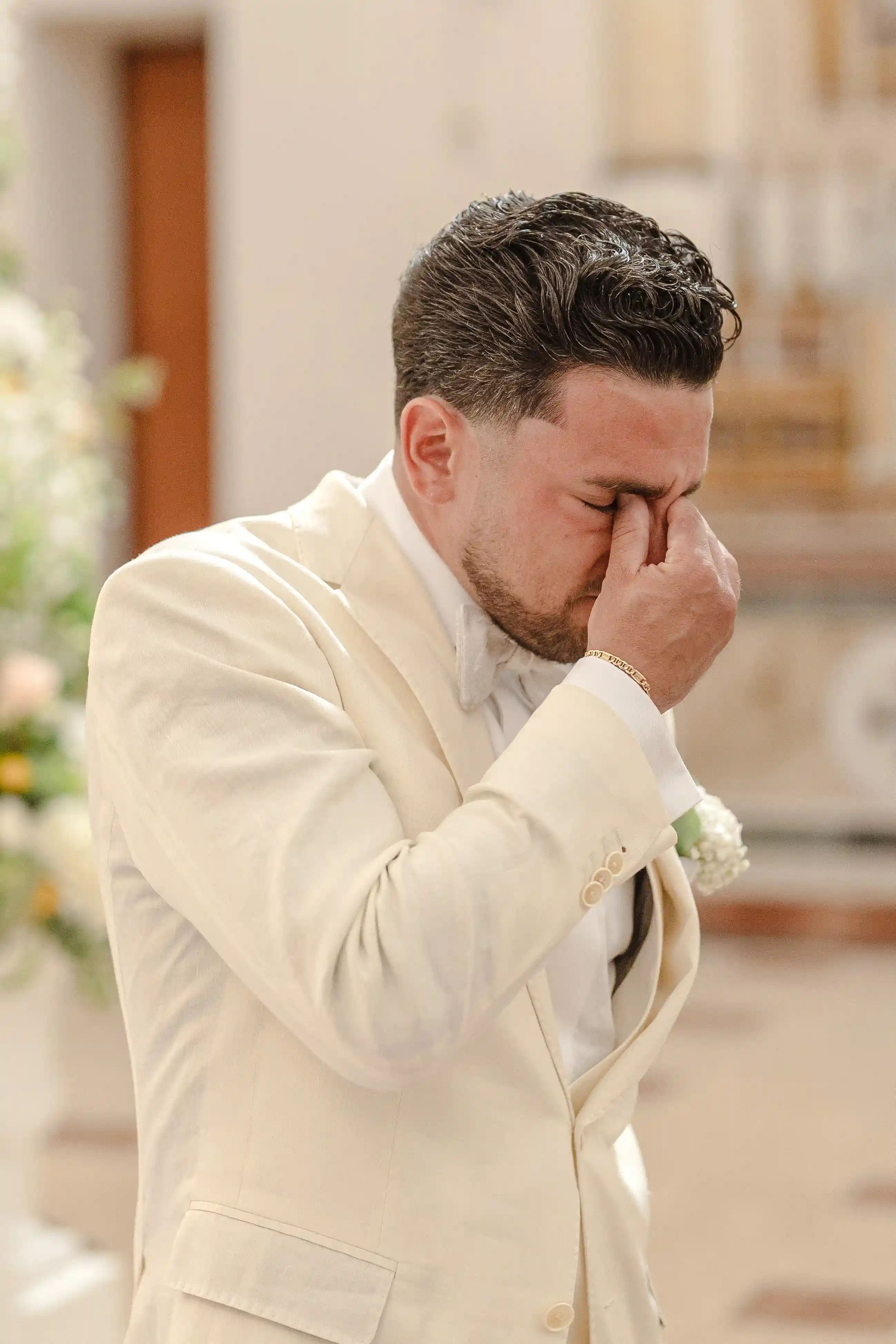 Emotional groom wiping away tears during the wedding ceremony