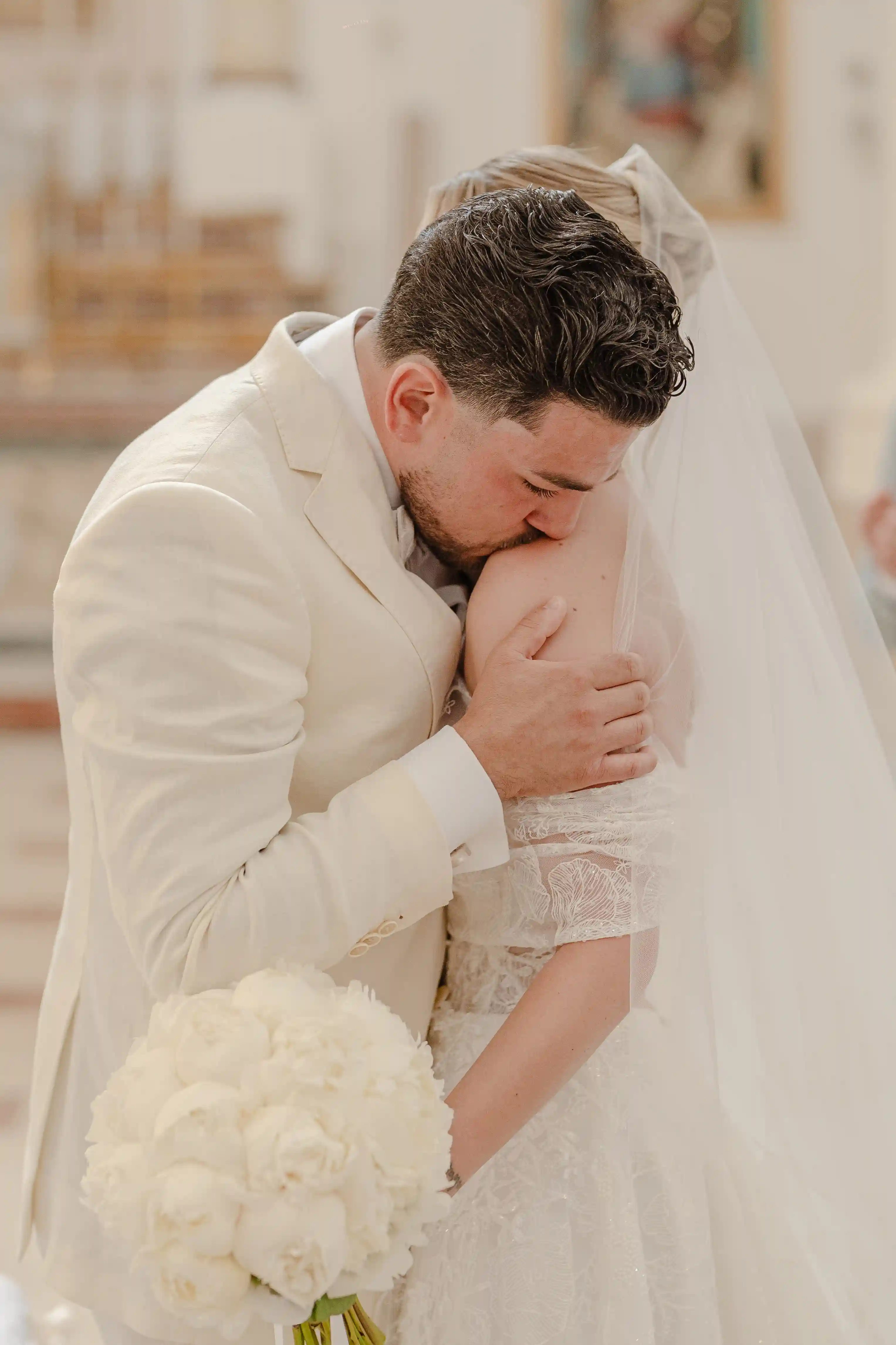 Groom kissing the bride’s shoulder during an intimate moment inside the church