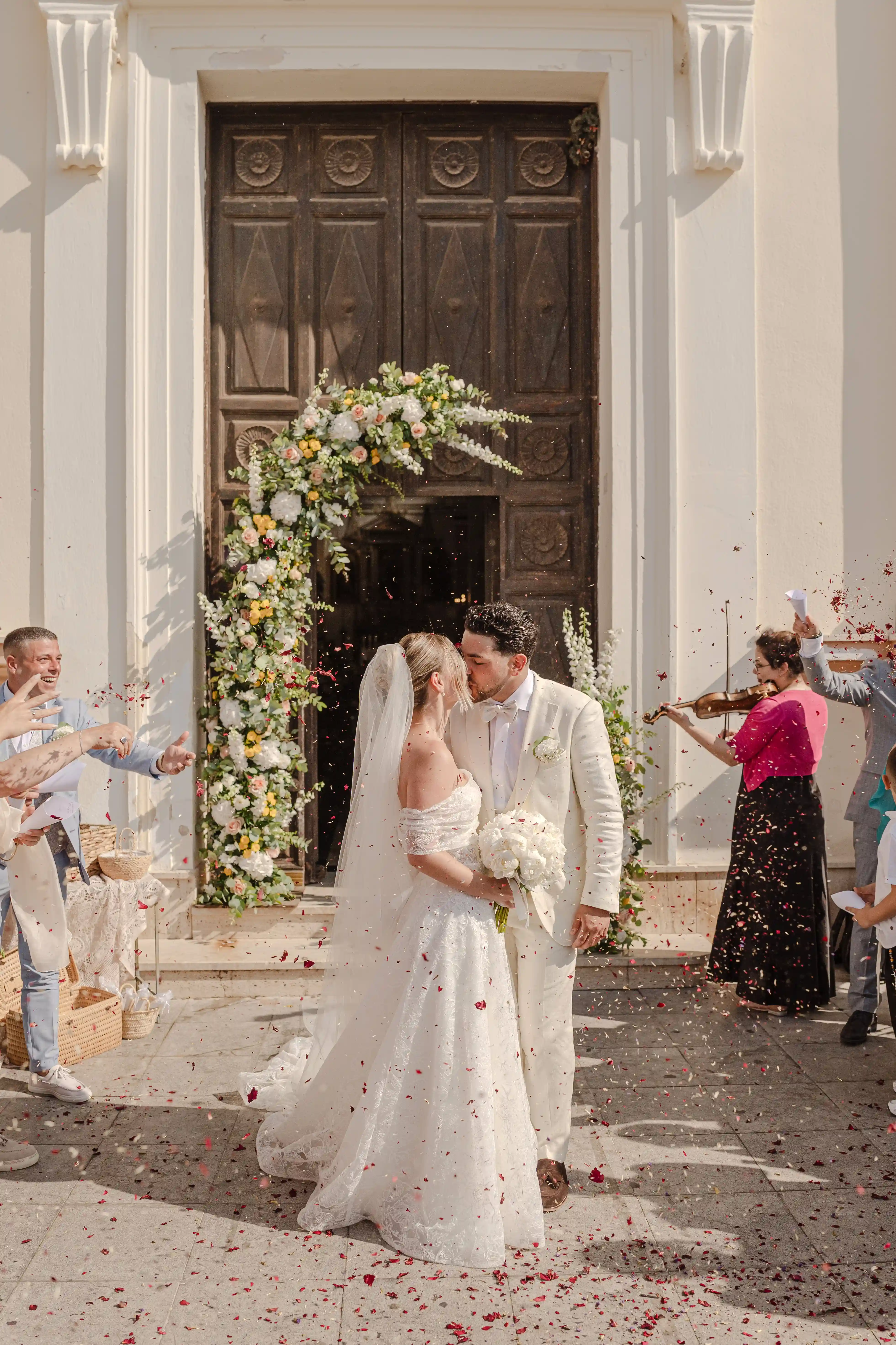 newlyweds sharing their first kiss outside church with confetti celebration