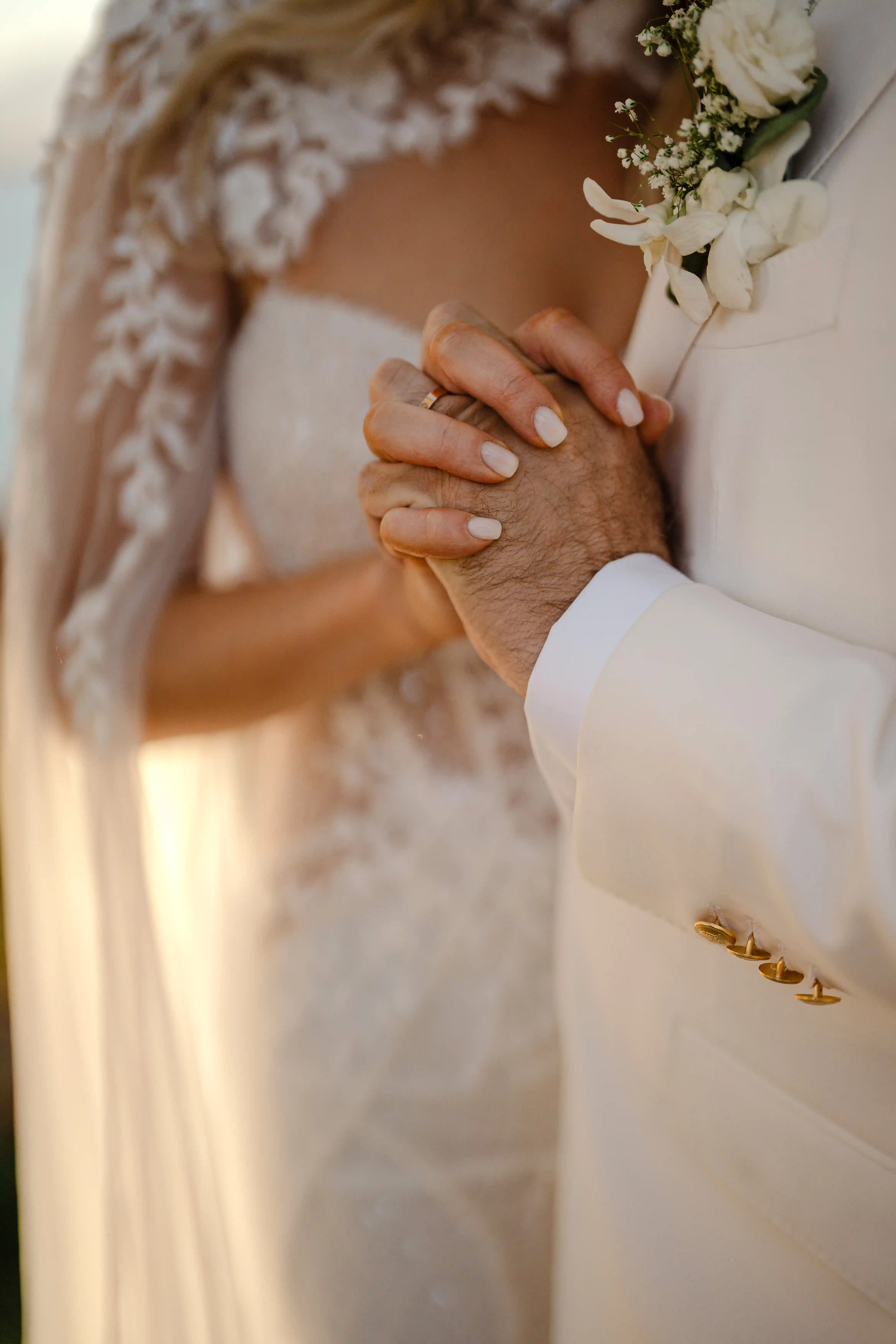 Close-up of bride and groom hands with wedding rings in warm sunset light in Sicily