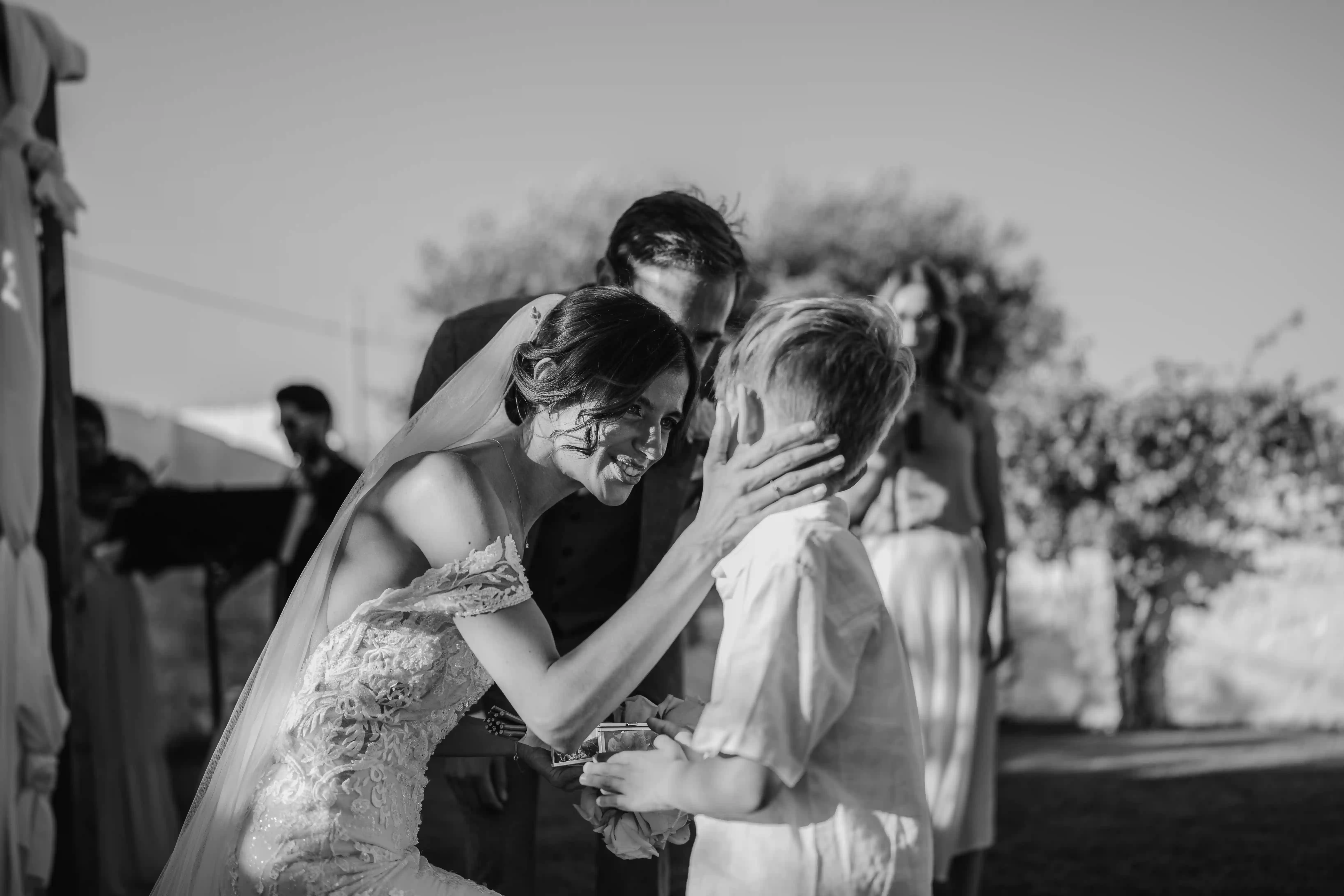 Emotional black and white moment bride talking to young boy during wedding ceremony in Puglia, Italy