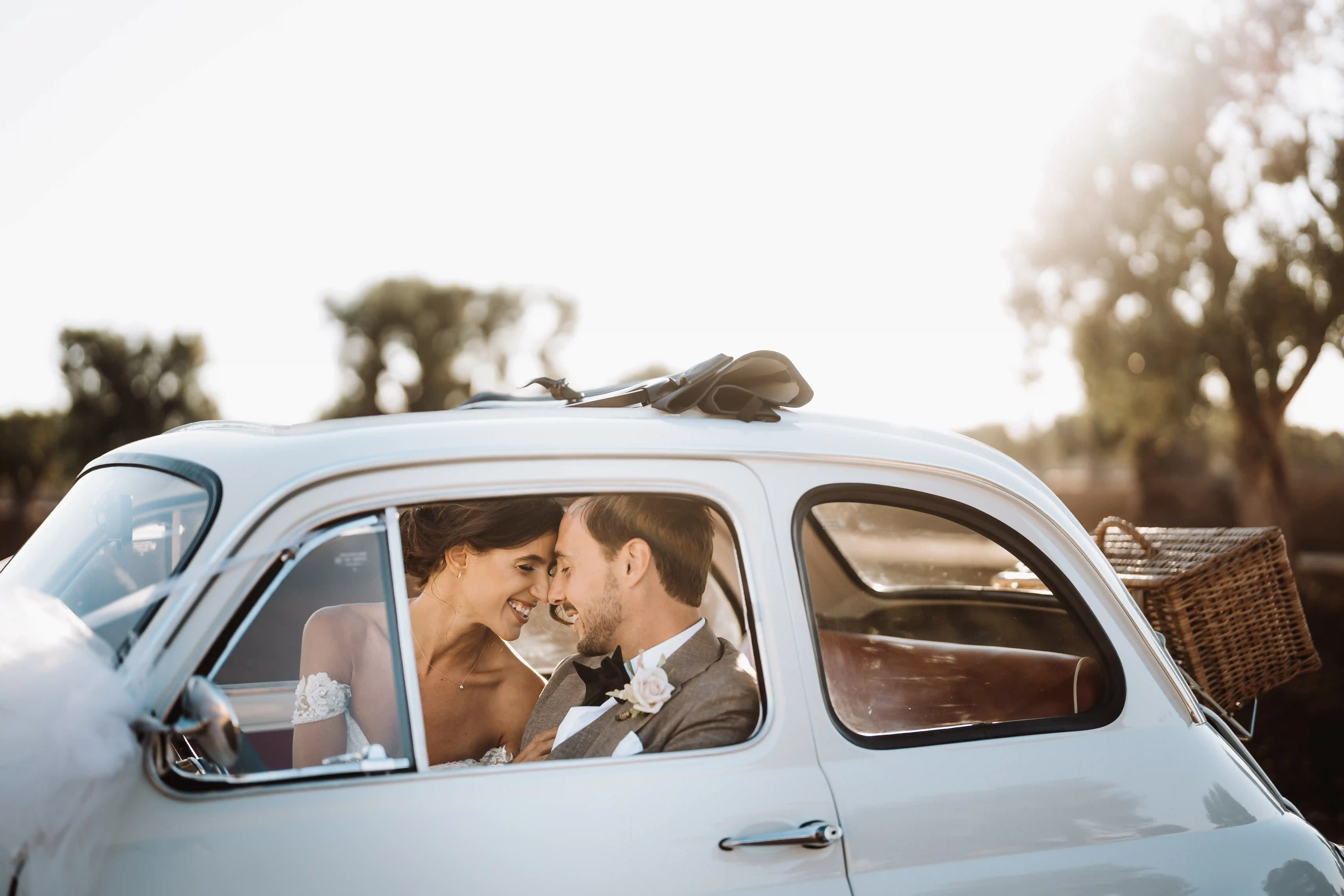 Newlyweds smiling inside vintage Fiat 500 car at sunset, Puglia destination wedding in Italy