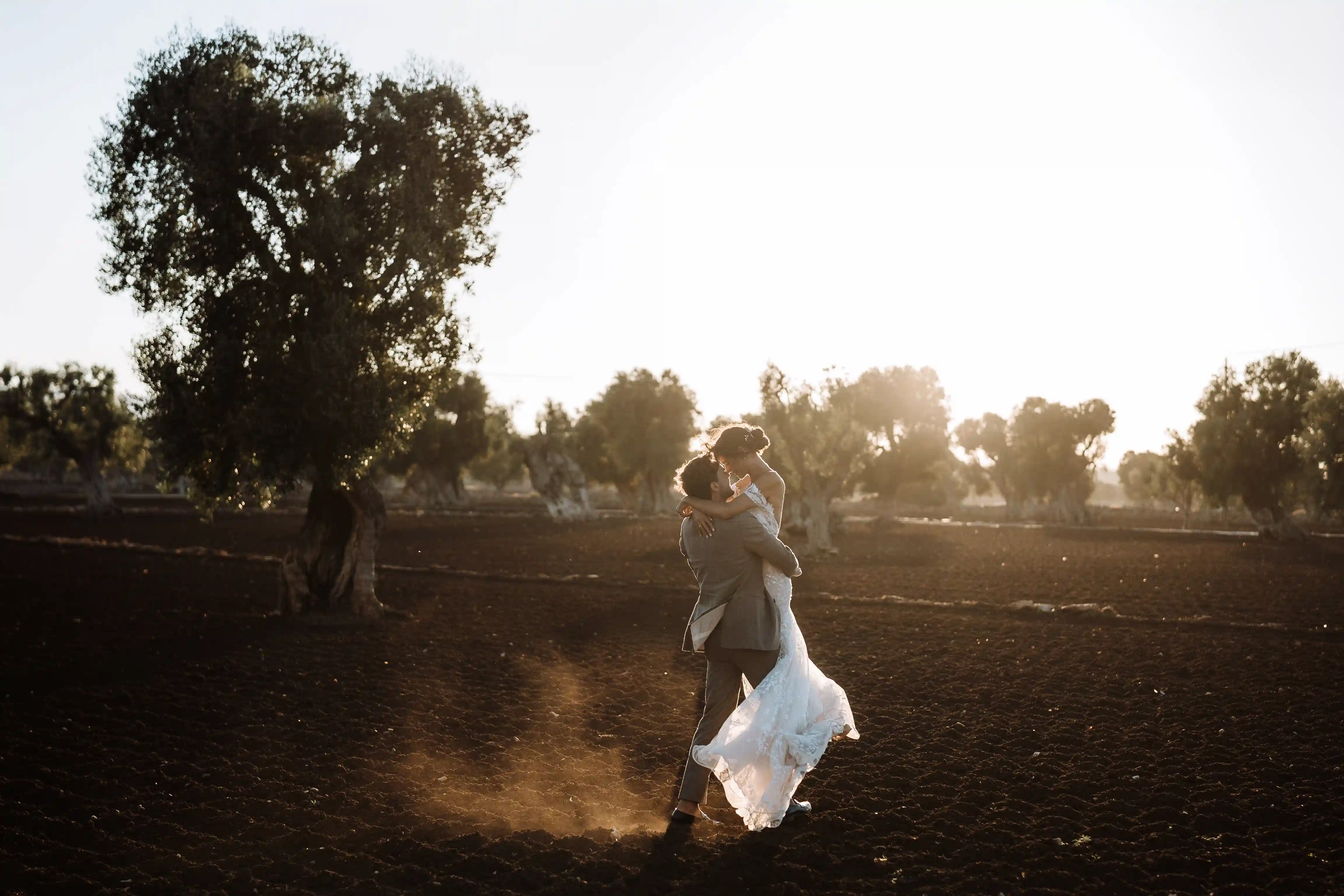 Wide shot of bride and groom in rustic Puglia landscape at sunset, romantic destination wedding in Italy