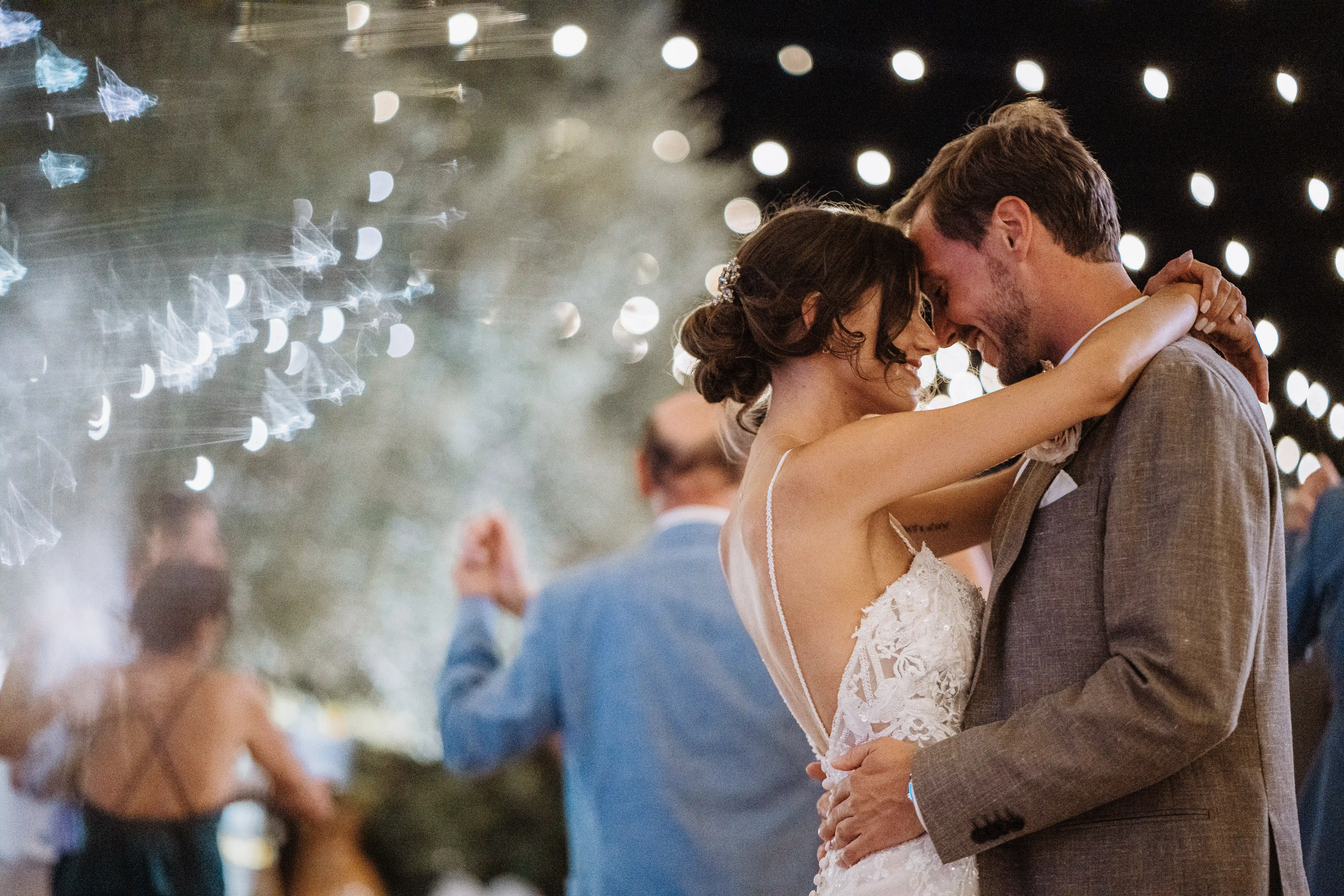 Romantic first dance of bride and groom with sparklers and lights in the background
