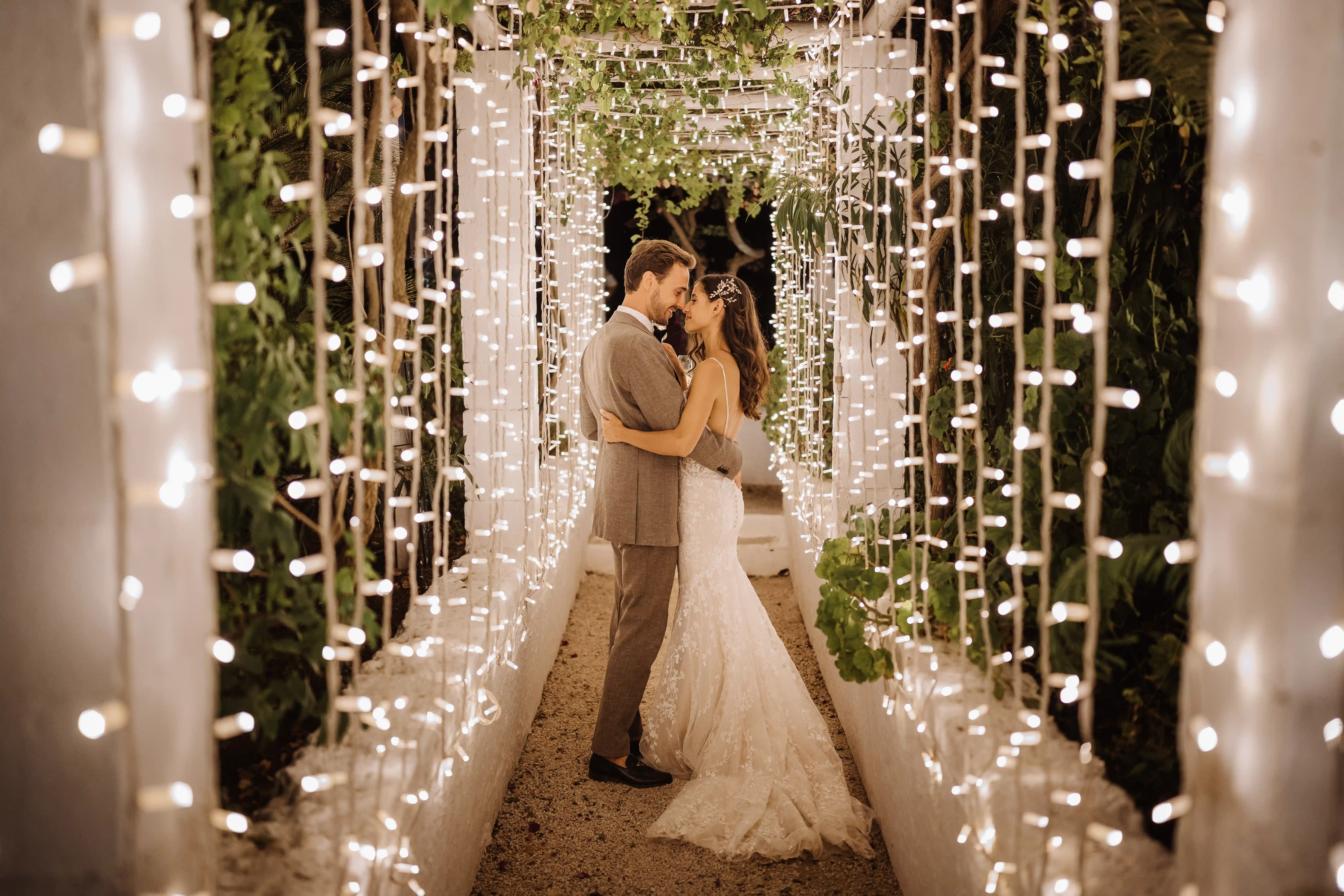 Bride and groom embracing under a tunnel of fairy lights at a Puglia masseria wedding