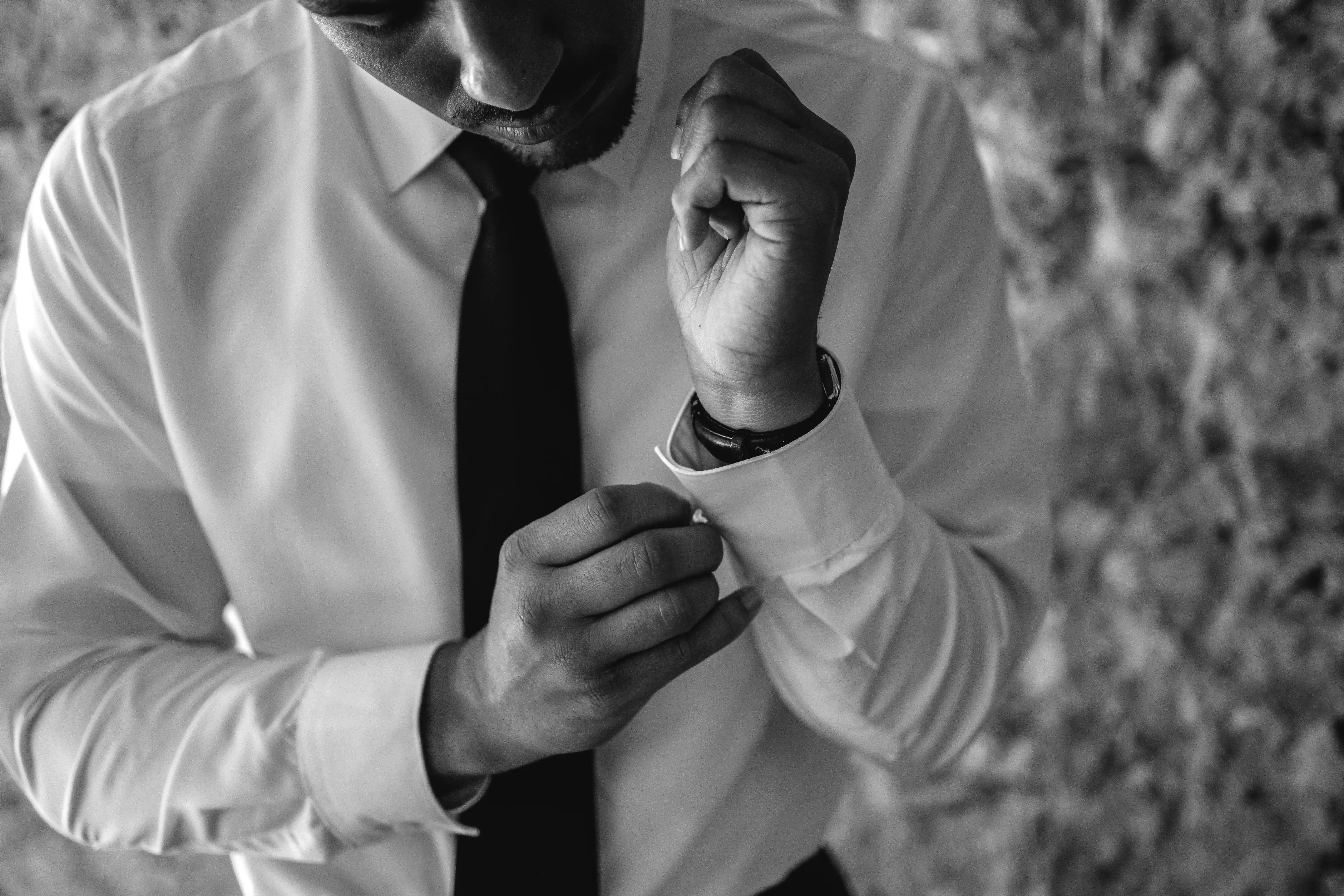 Groom adjusting cufflinks in a timeless black and white portrait before an intimate Sicilian elopement.
