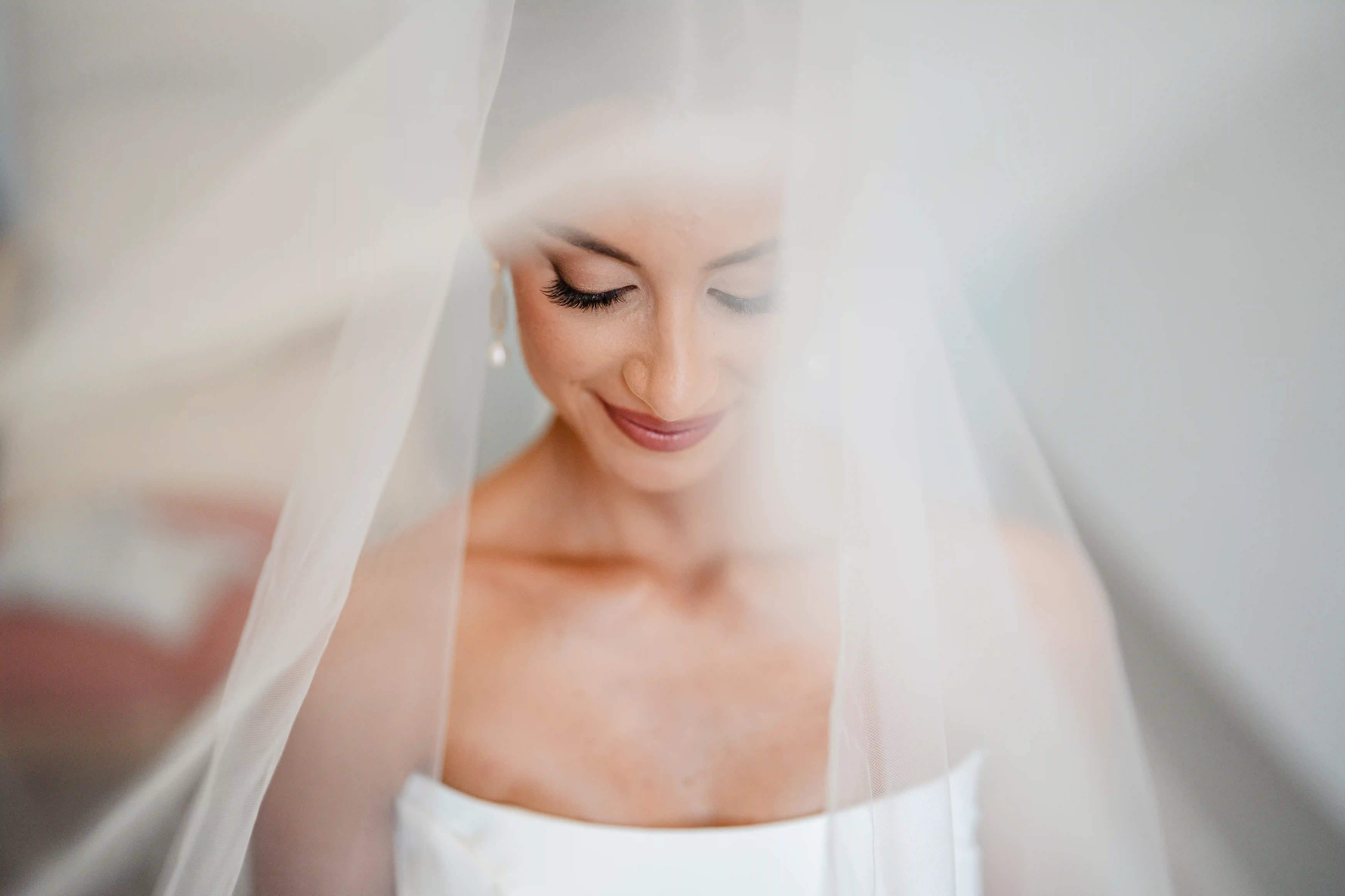 Soft and ethereal bridal portrait with veil gently framing the bride’s face in natural light.