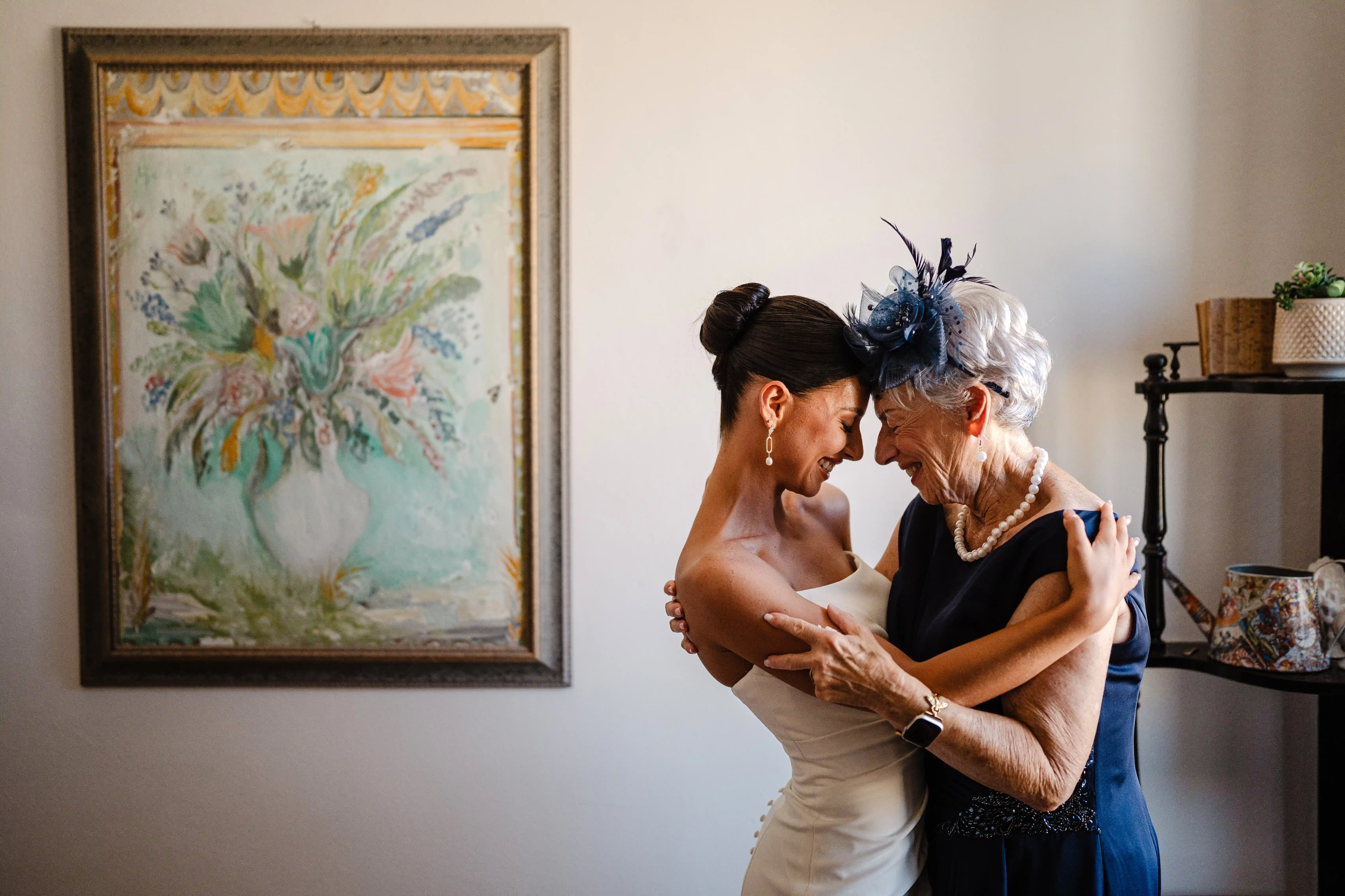 Bride sharing a tender embrace with an elderly family member during emotional pre-ceremony moments.