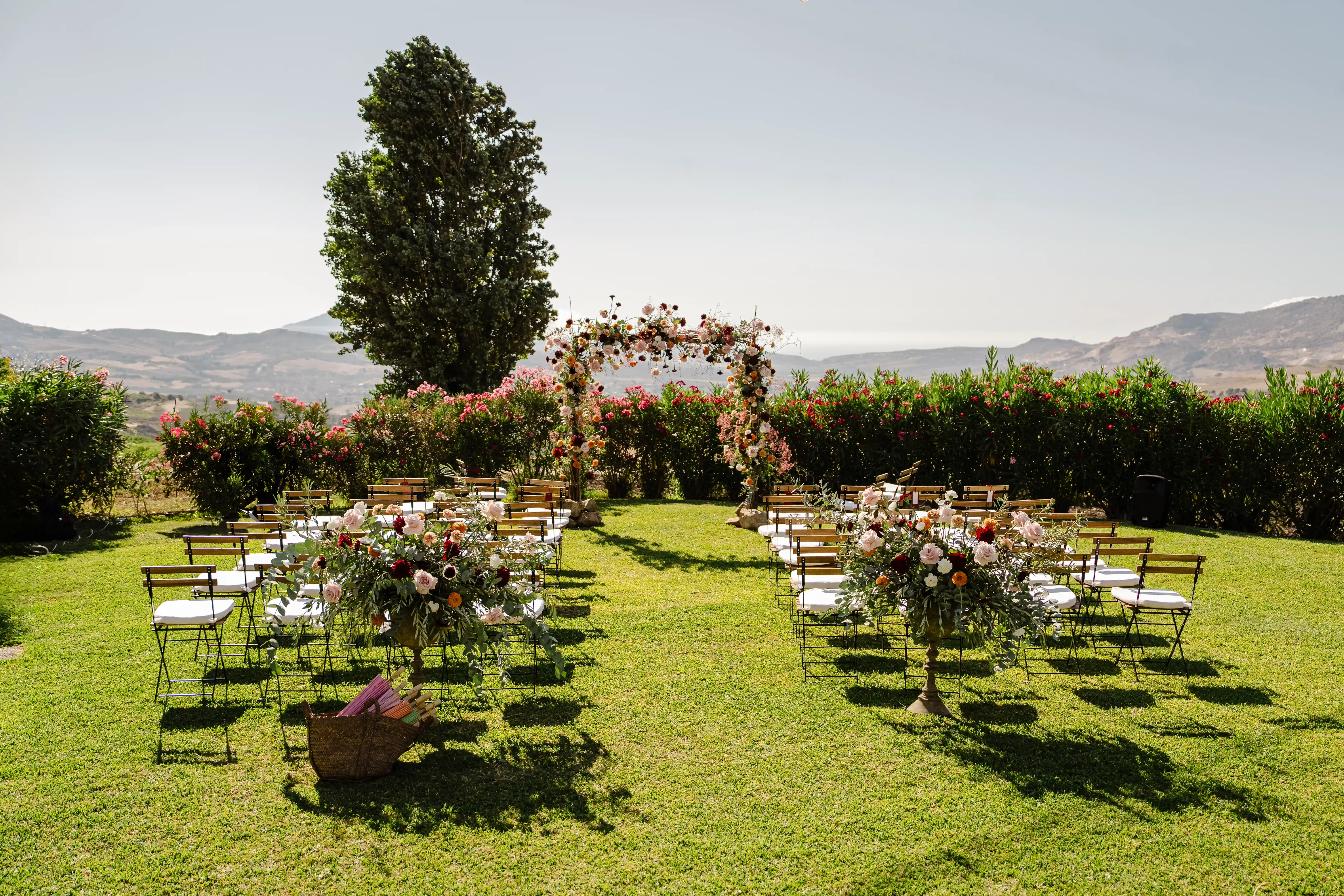 Outdoor elopement ceremony setup in the Sicilian countryside with floral arch and panoramic views.
